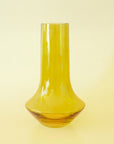 A glass green vase with a bottle neck and wide base. 