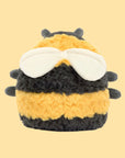 A brownish black and yellow bee shaped stuffed animal with an adorable smiling face and wings. 