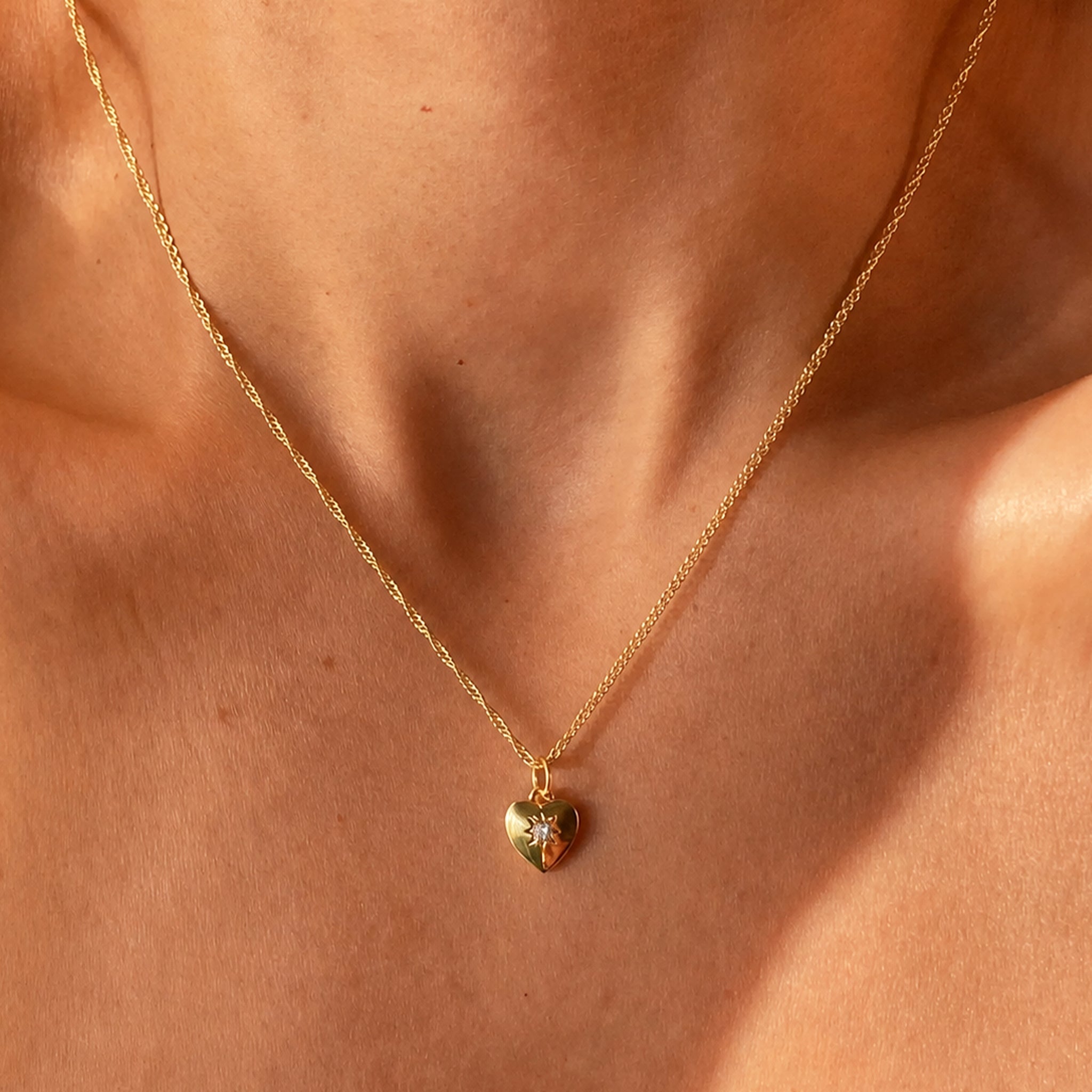 Gold necklace with a heart-shaped pendant on a person's neck