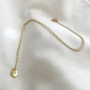 Gold necklace with a heart-shaped pendant on a white fabric background