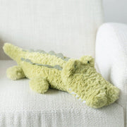 A green cuddly stuffed animal shaped alligator.