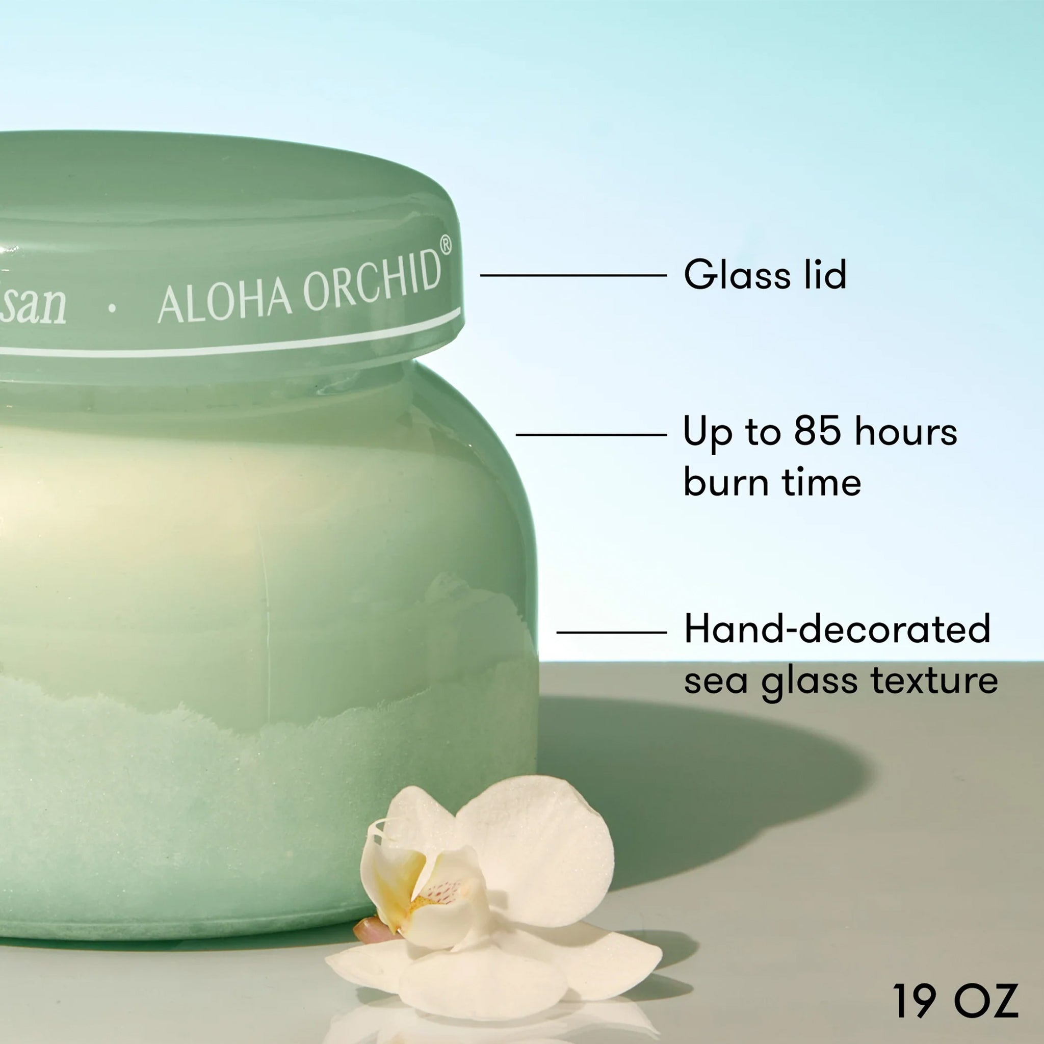 Green candle jar with 'Aloha Orchid' branding, labeled features, and a white flower on a light background.