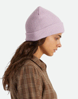 On a white background is a light purple knit beanie worn on a model. 