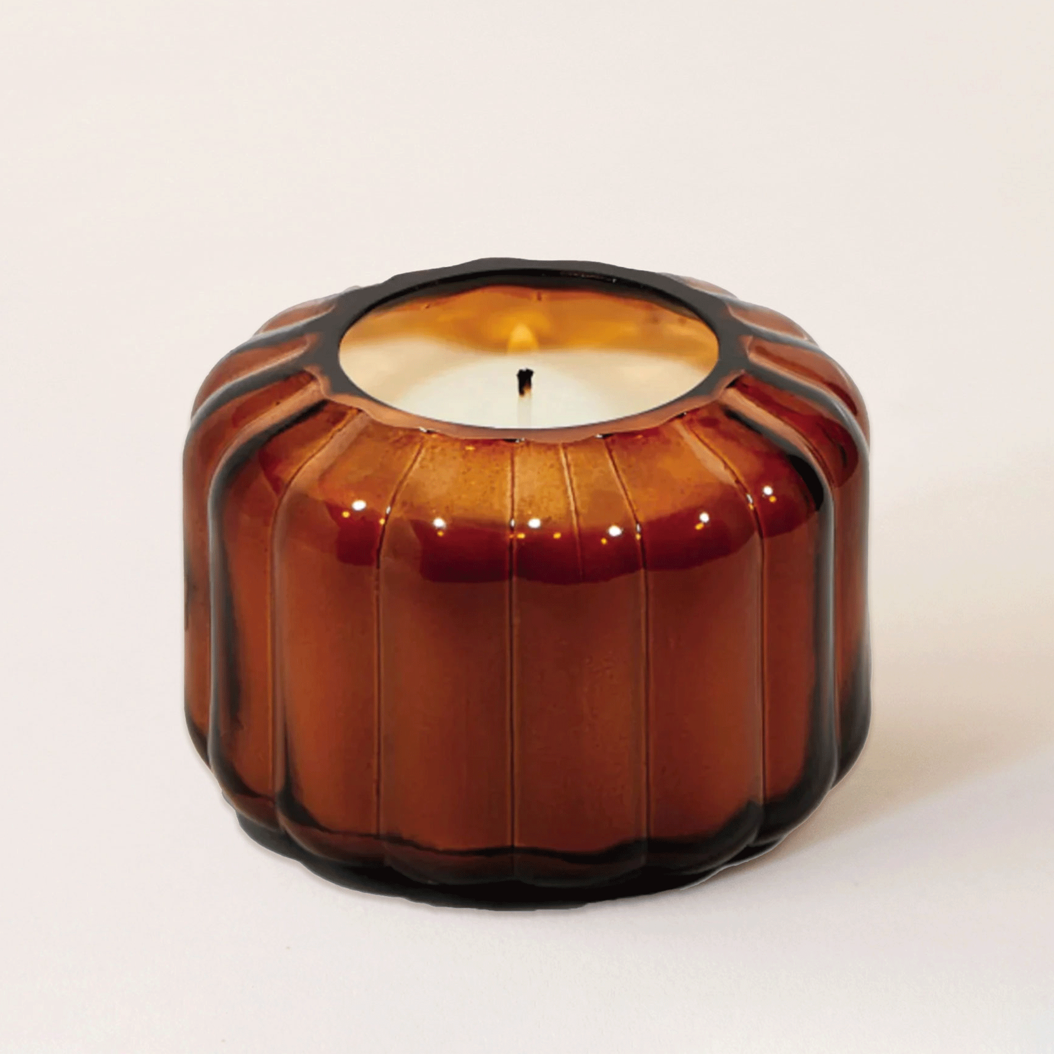 An amber glass candle with a ribbed texture and a single wick.