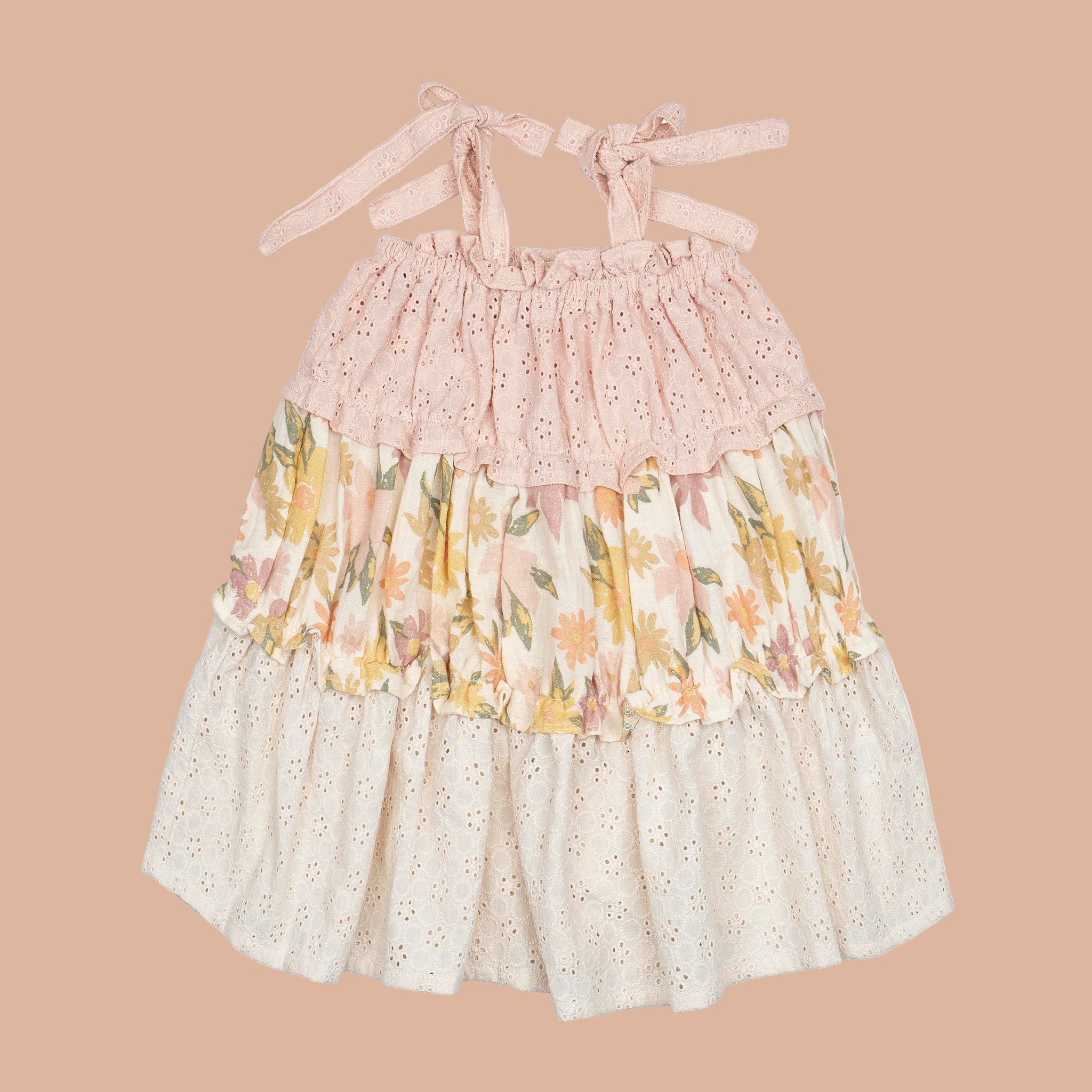 A light pink and yellow floral tiered dress for little girls and babies with tie shoulder details. 