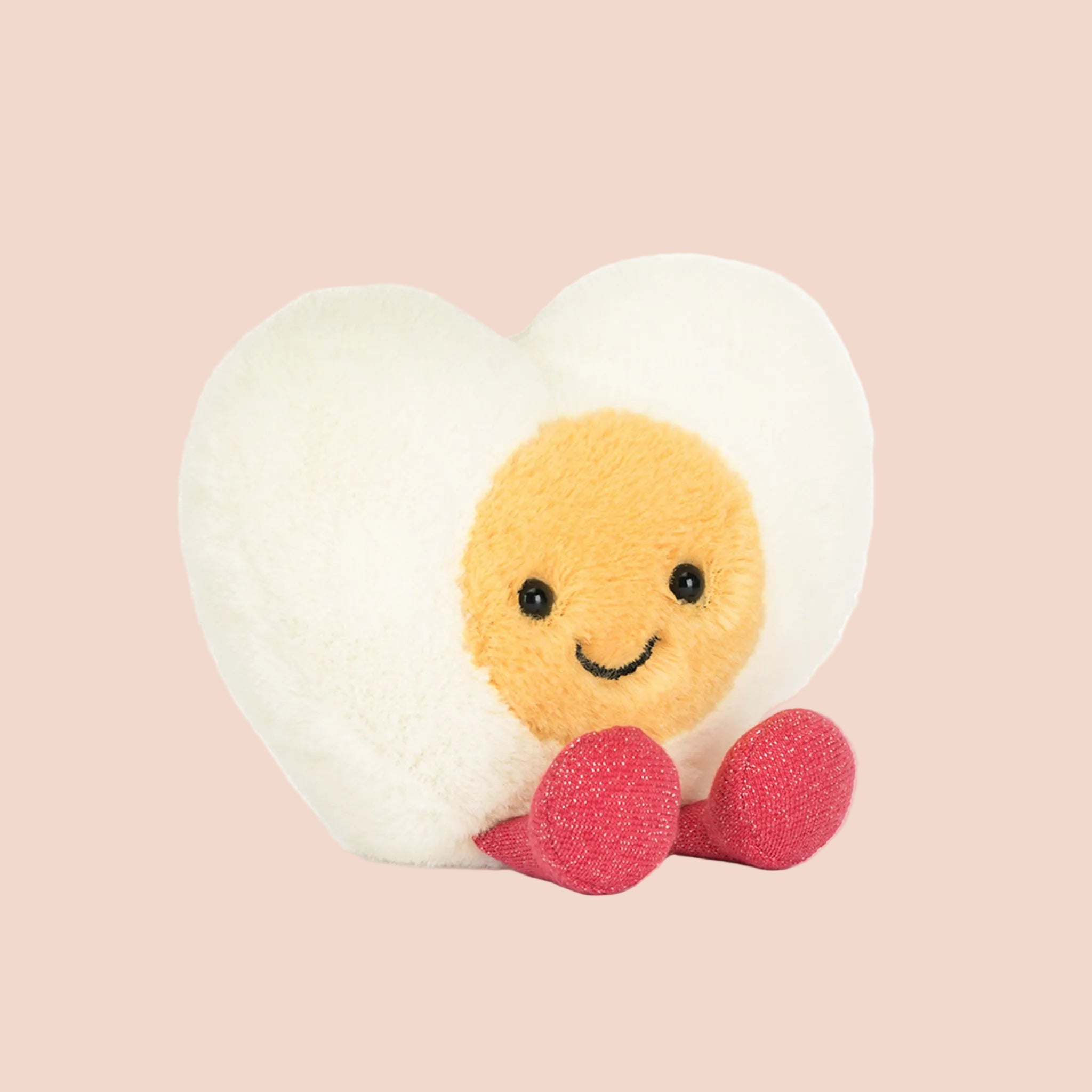 A white and yellow heart egg shaped stuffed toy with red legs and feet and a smiling face. 