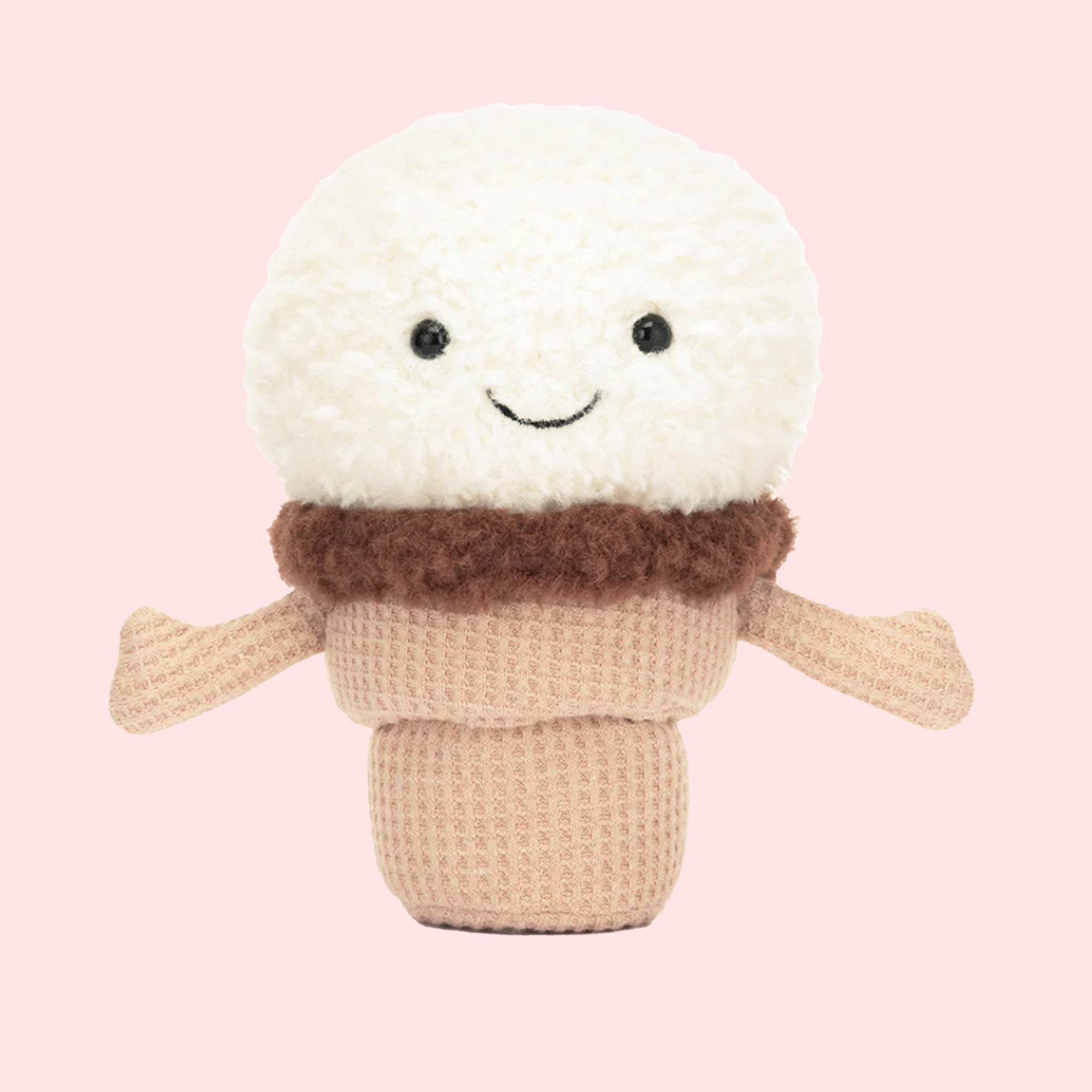 On a pink background is a photo of an ice cream cone shaped stuffed animal with a smiling face and little waffle cone textured arms. 