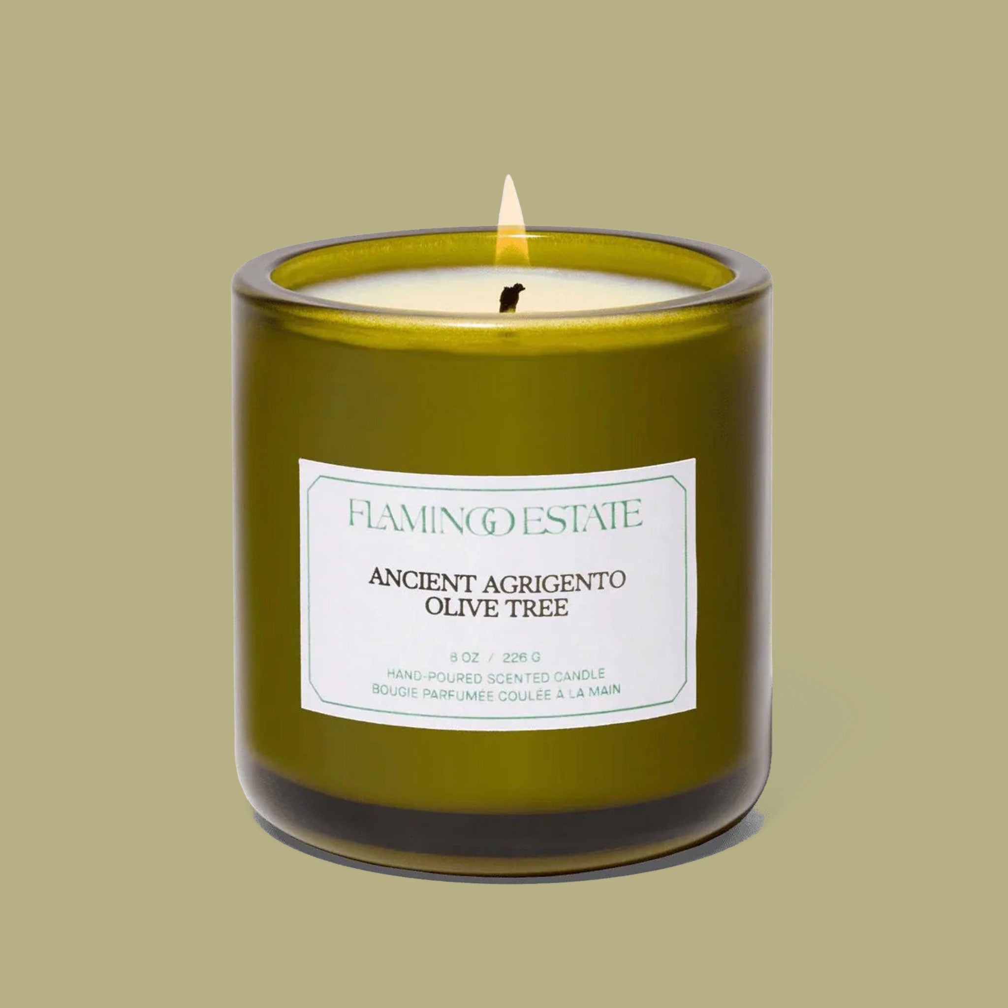 A green glass candle sits in the middle of image with a label that reads, "Ancient Agrigento Olive Tree"
