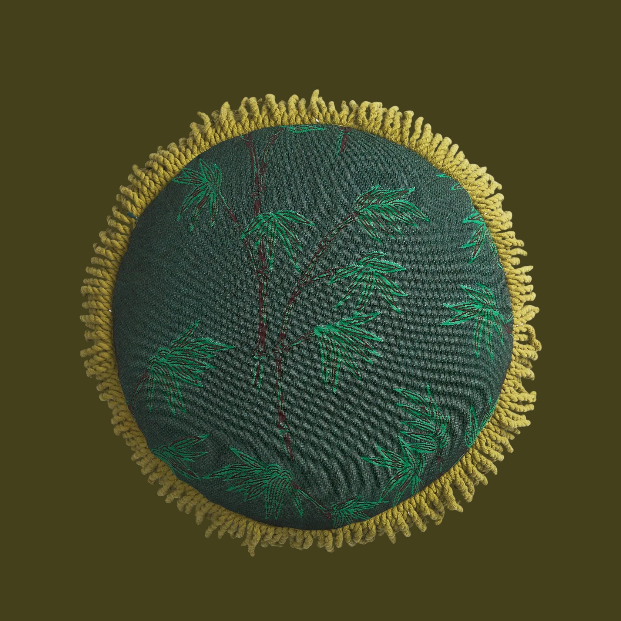 Round green cushion with embroidered patterns on a white background