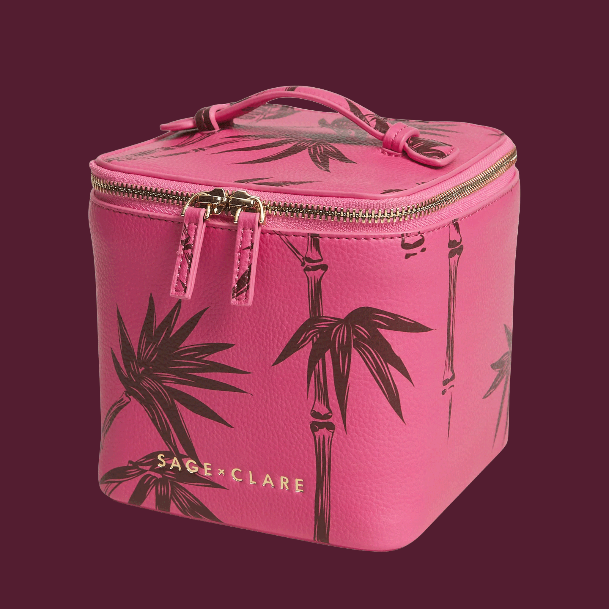 a pink vanity case with palm details and a gold zipper.  background color is aubergine.