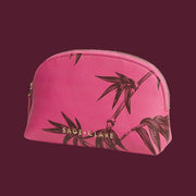 A pink cosmetic bag with palm details on an aubergine ground.