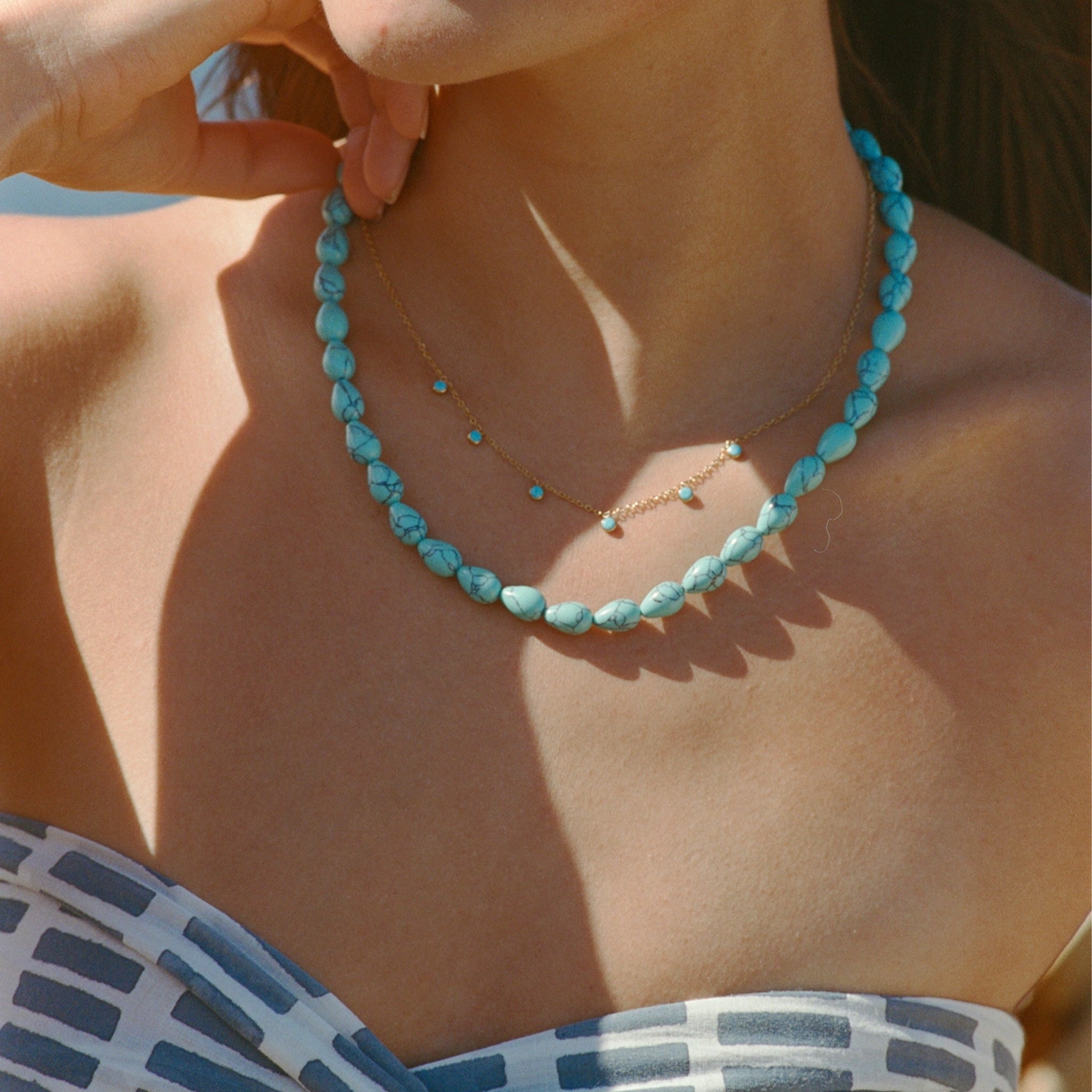 A model wearing a turquoise blue beaded necklace. 