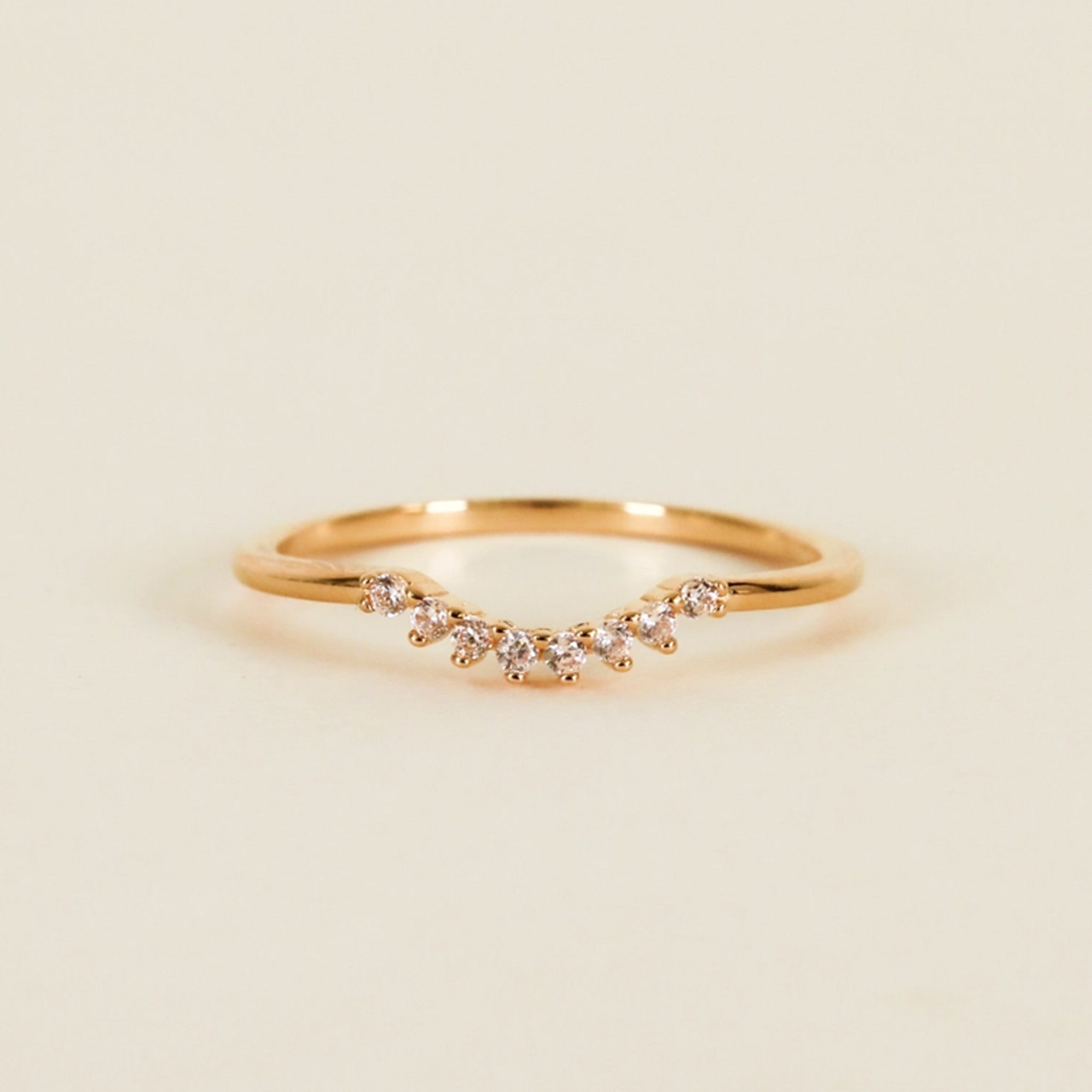 On a tan background is a gold ring with small cubic zirconias along the small dip. 