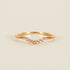 On a tan background is a gold ring with small cubic zirconias along the small dip. 