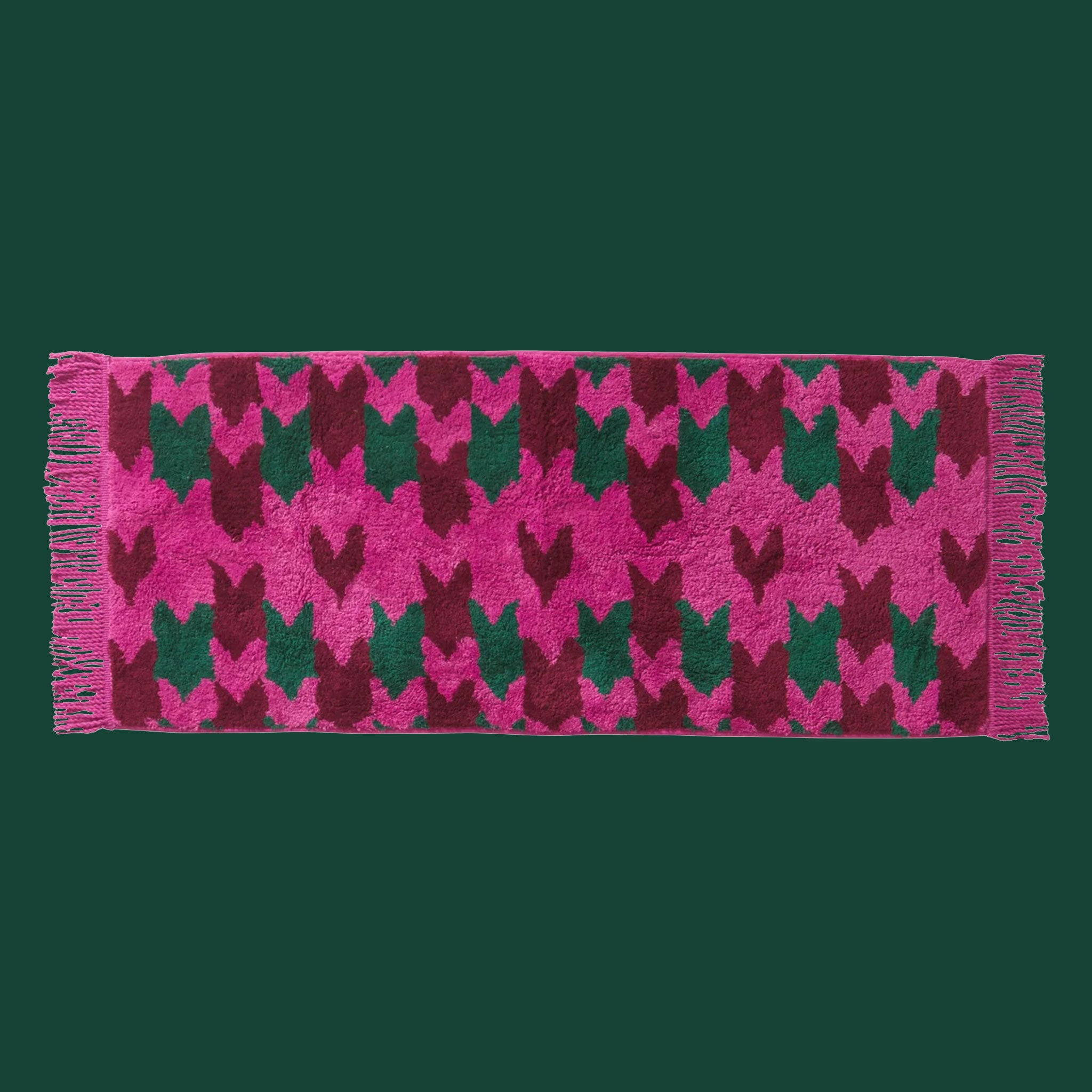 Bright pink, dark pink and dark teal bath mat with pink fringe. 