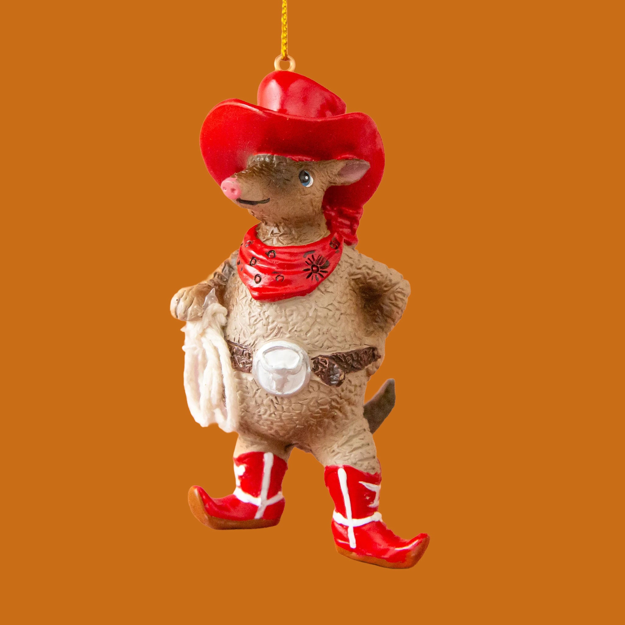 A brown resin armadillo shaped ornament dressed in a red western outfit. 