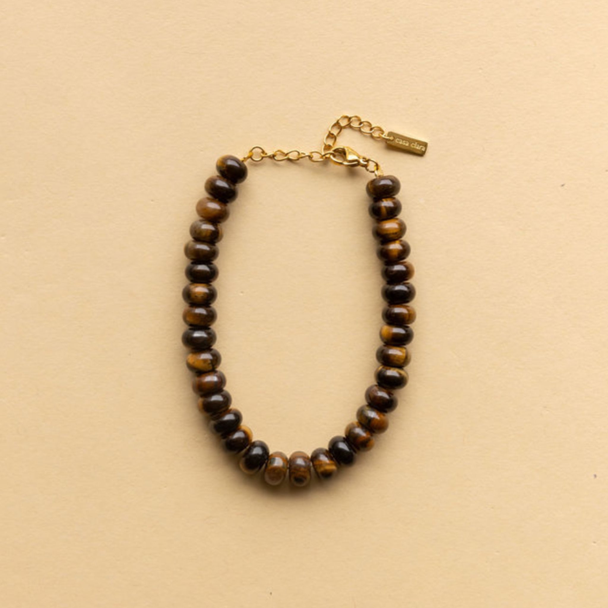 A round wood bead bracelet with a gold clasp. 