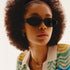 A pair of black oval shaped sunglasses with a dark grey lens. 