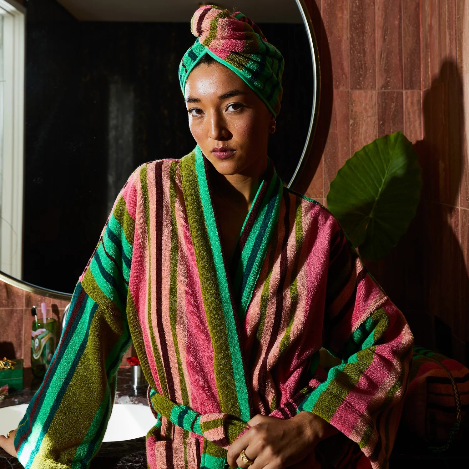 Person wearing a striped robe and matching towel wrap, standing in a bathroom in front of a mirror.
