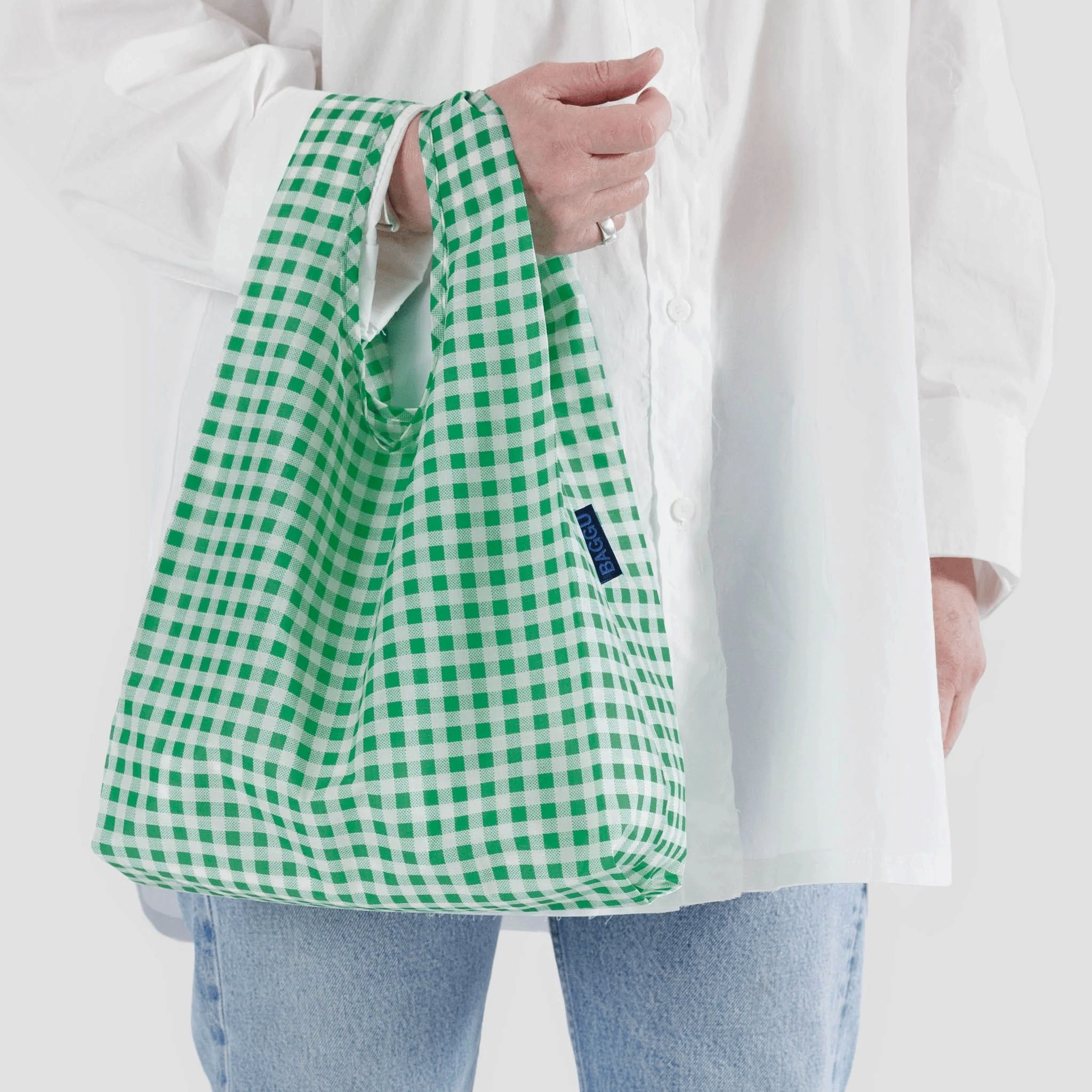 A model holding a green and white gingham printed nylon tote bag.