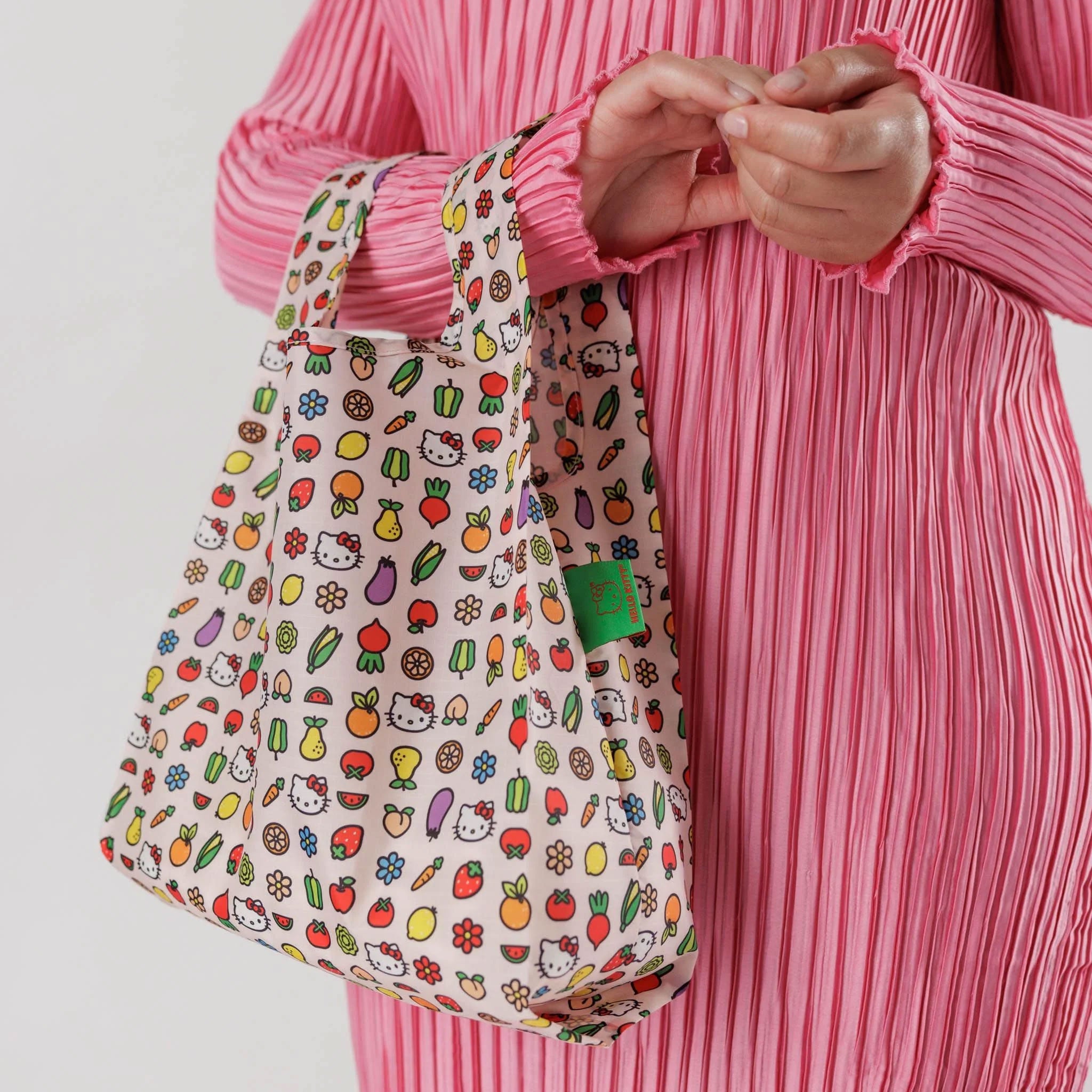 A model holding a a nylon tote bag with hello kitty icon prints. 