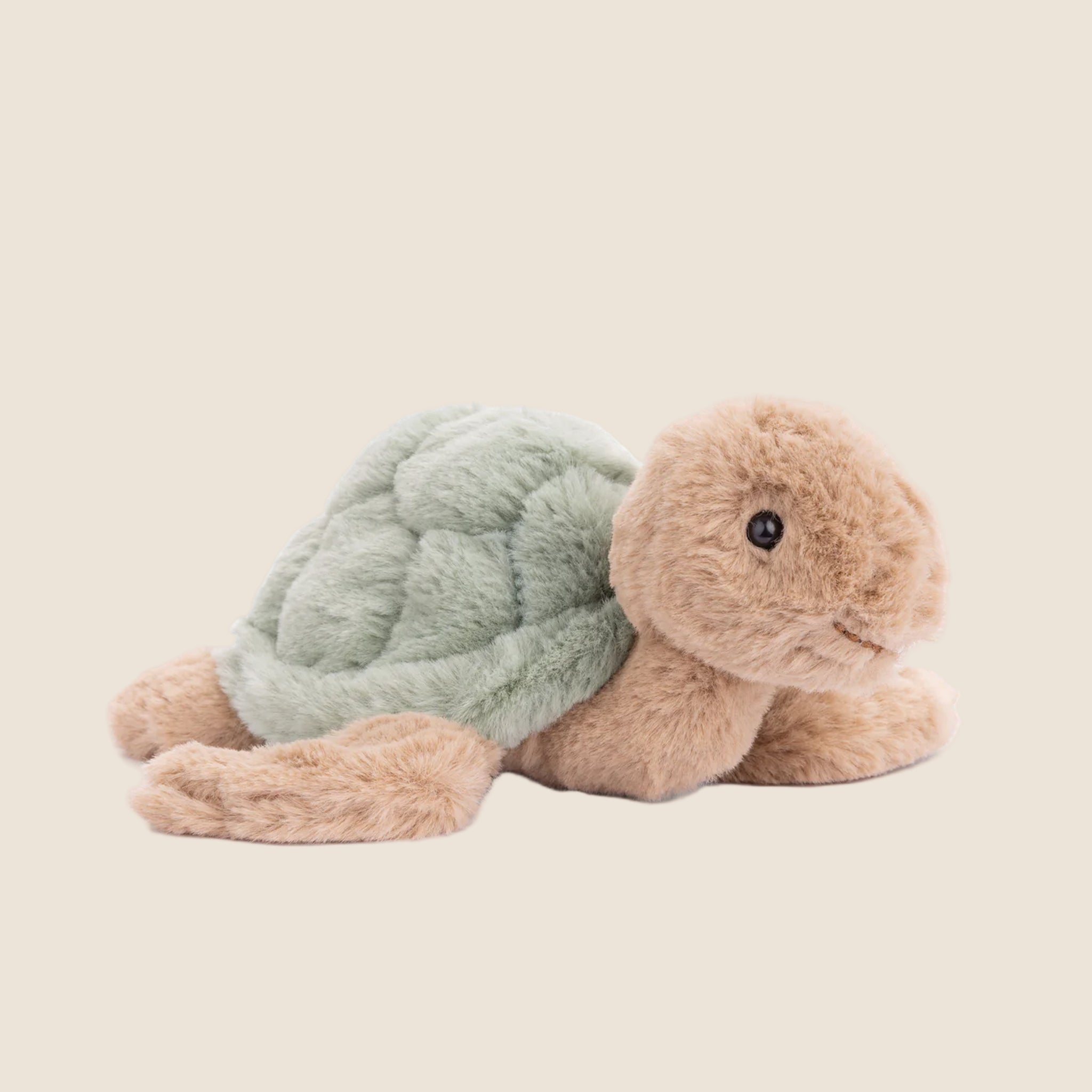 A tan and green turtle shaped stuffed animal toy. 