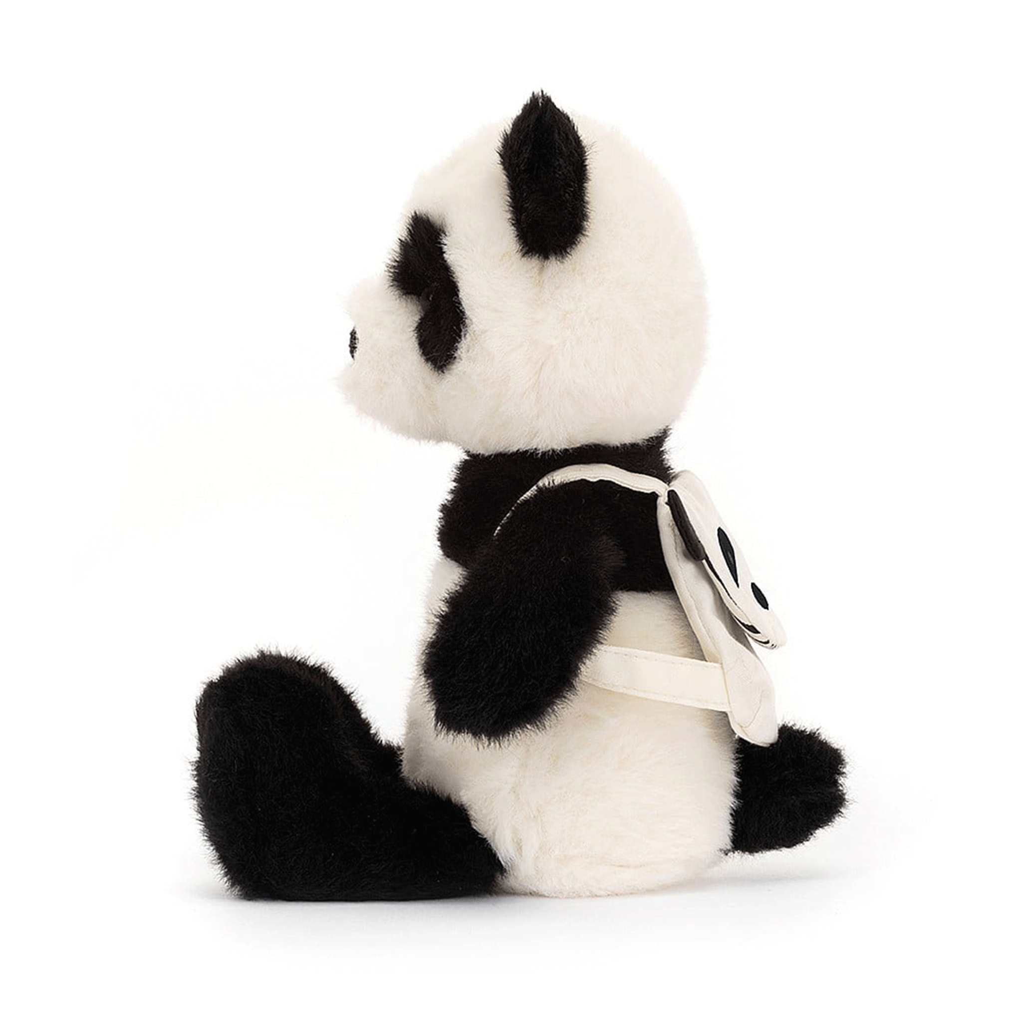 On a white background is a black and white panda stuffed toy wearing a panda backpack.