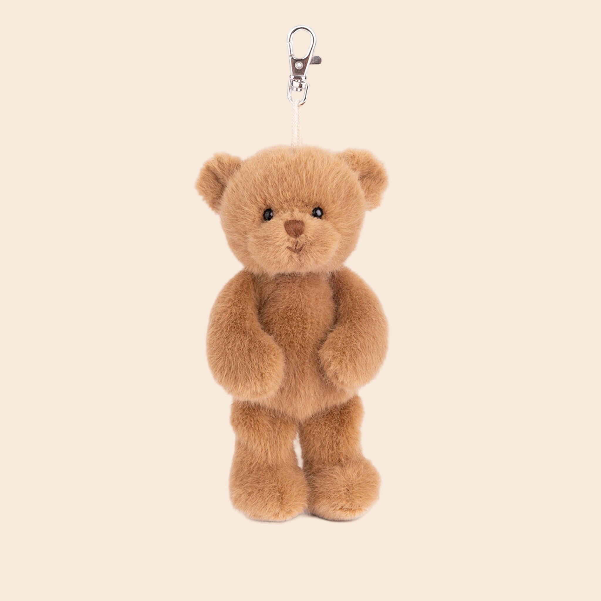 A bag charm in the shape of a fuzzy light brown bear. 