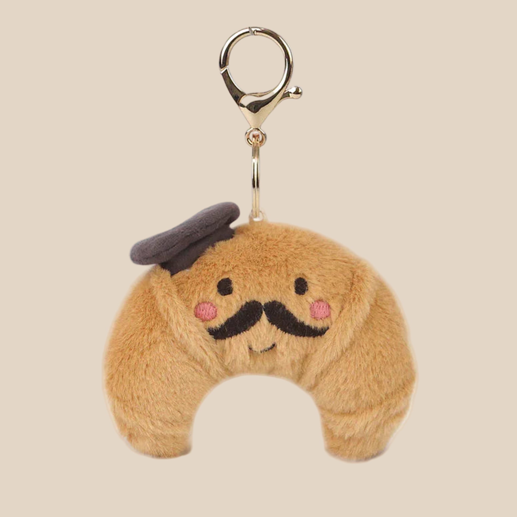 A brown croissant shaped stuffed bag charm keychain. 