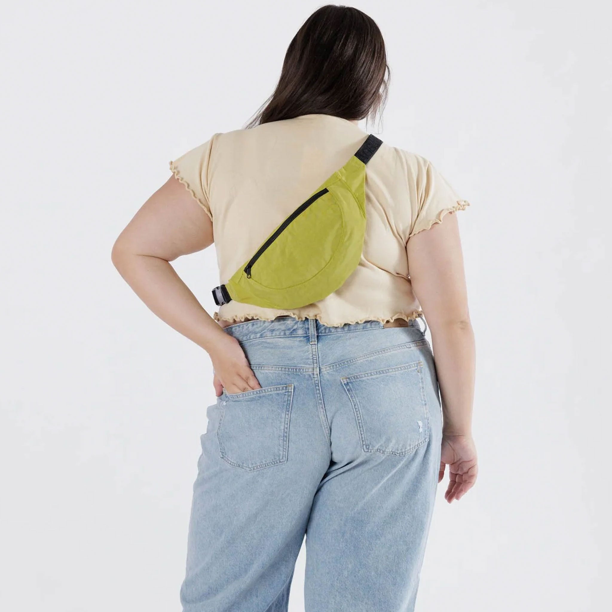 A model wearing a a crescent shaped fanny pack in lime green color with black strap.