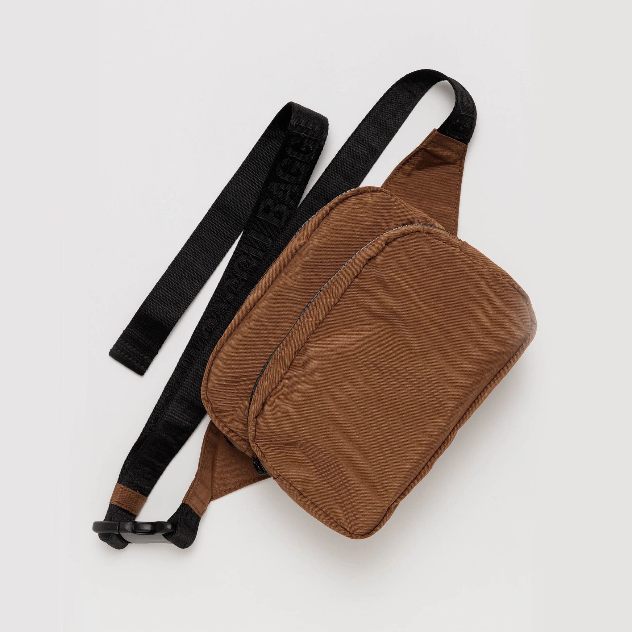 On a white background is a brown fanny pack with two zippers with a black strap. 