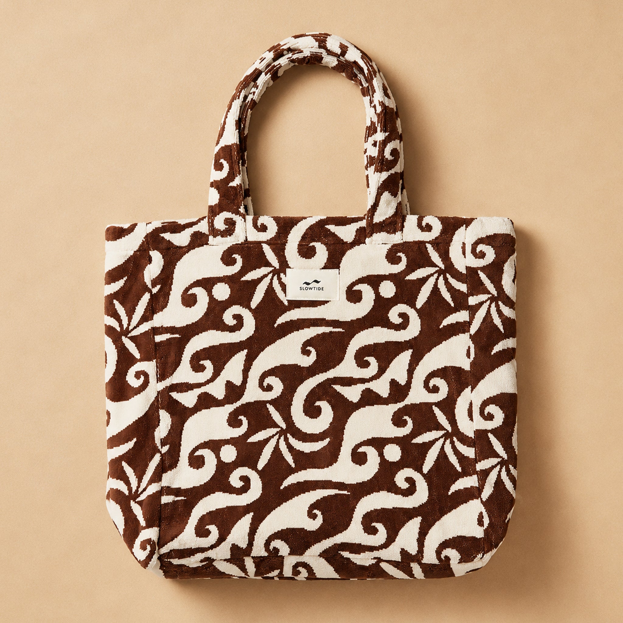 a brown and white patterned bag with a tropical background