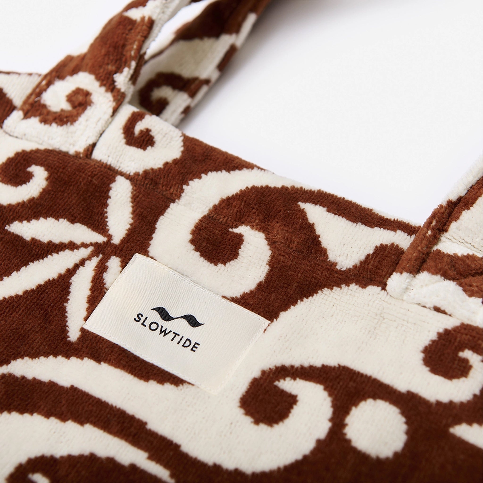 a brown and white patterned bag with a tropical background