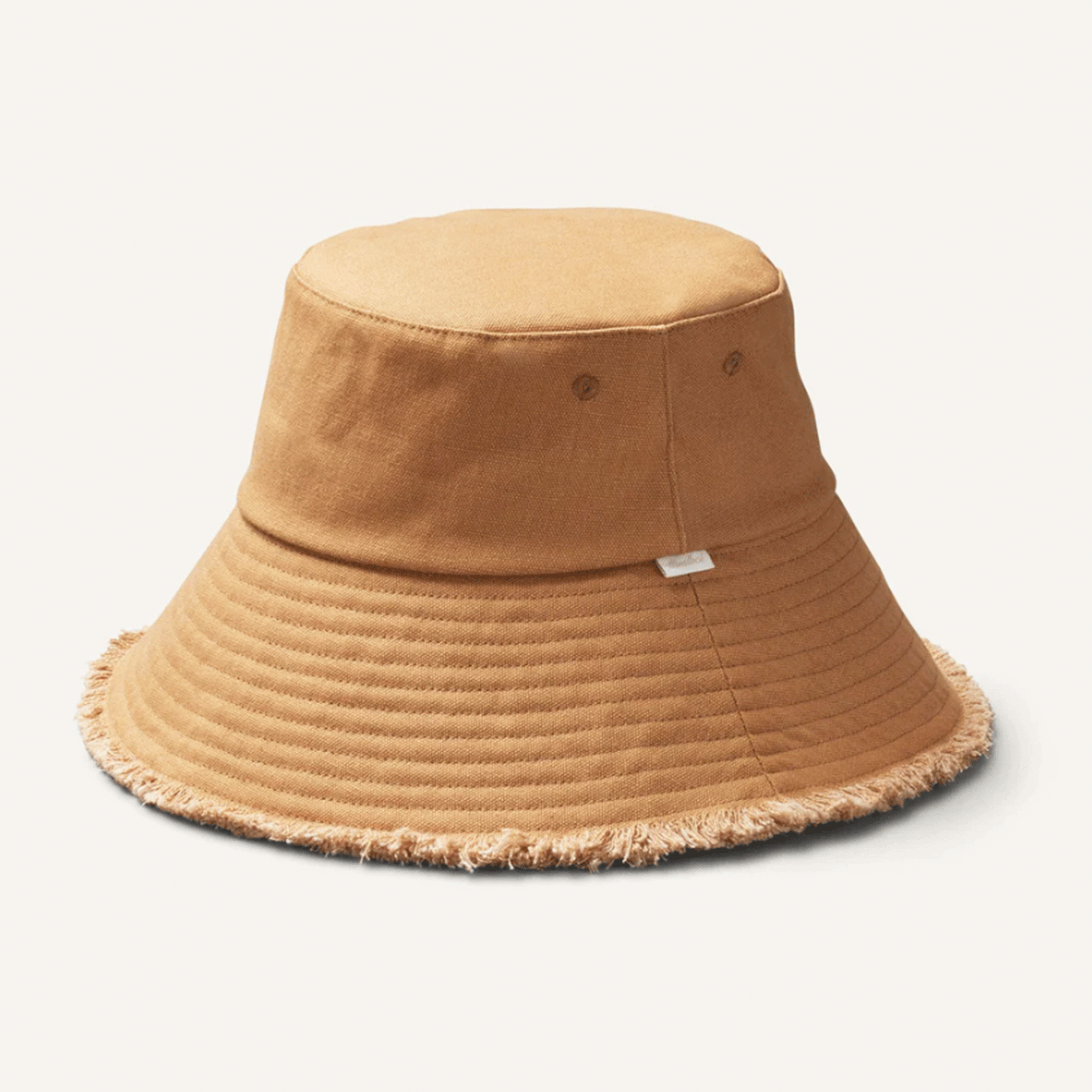 On a white background is a camel colored bucket hat with a subtle fringe around the edge of the brim. 
