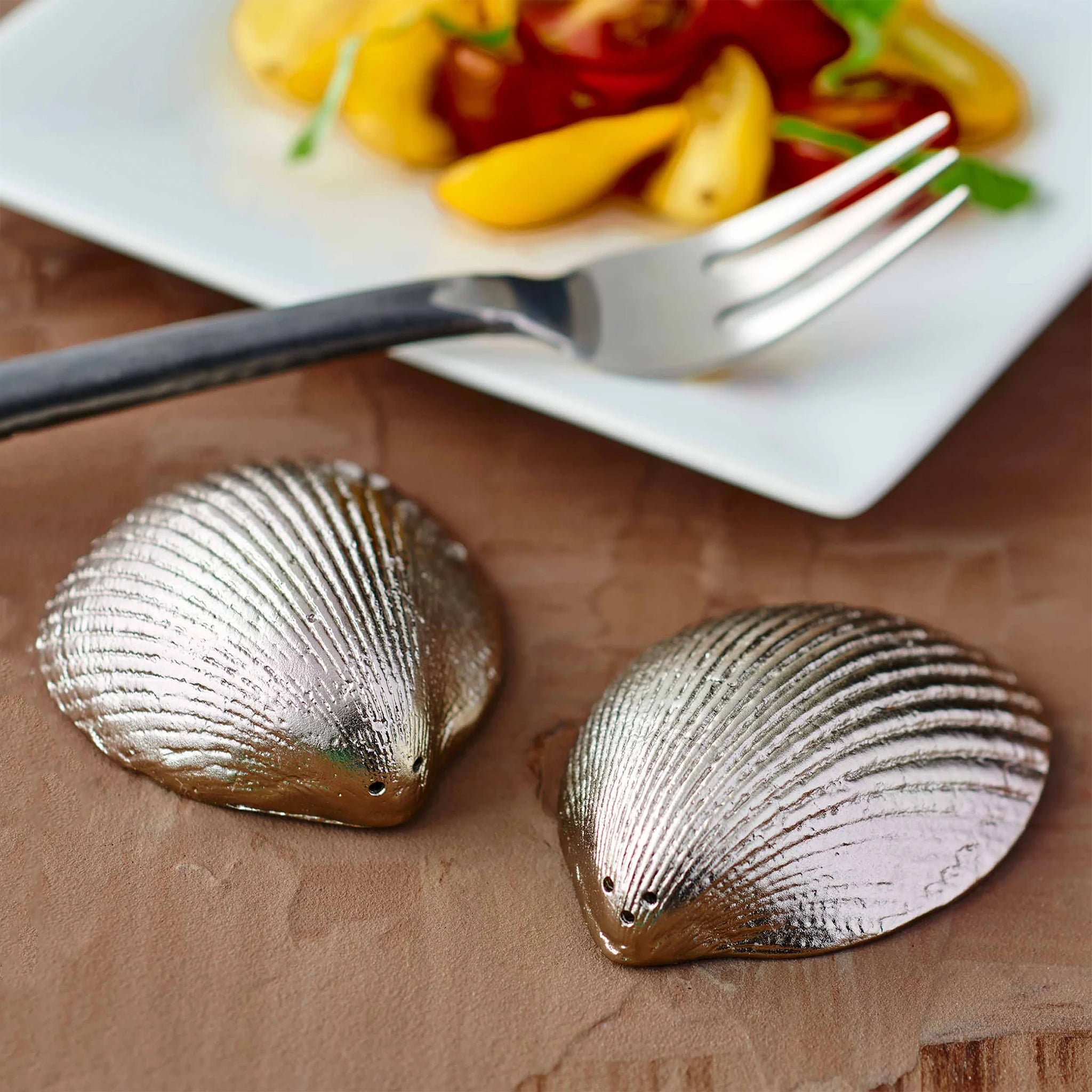 A silver pair of  shell shaped salt and pepper shakers. 