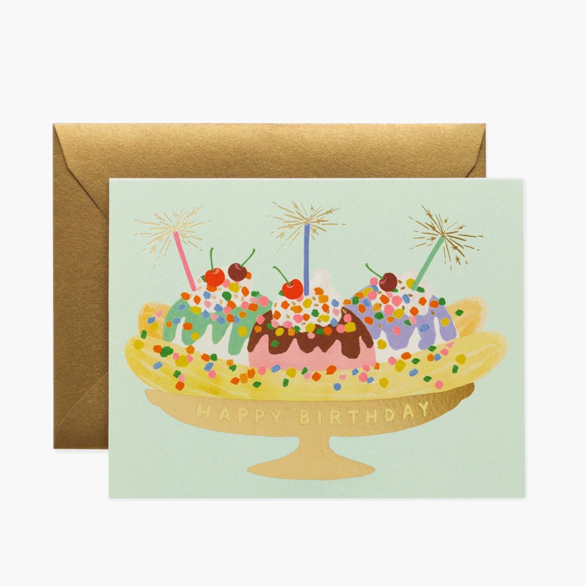 On a white background is a mint green birthday card with an illustration of a banana split along with gold foiled text that reads, &quot;Happy Birthday&quot;.