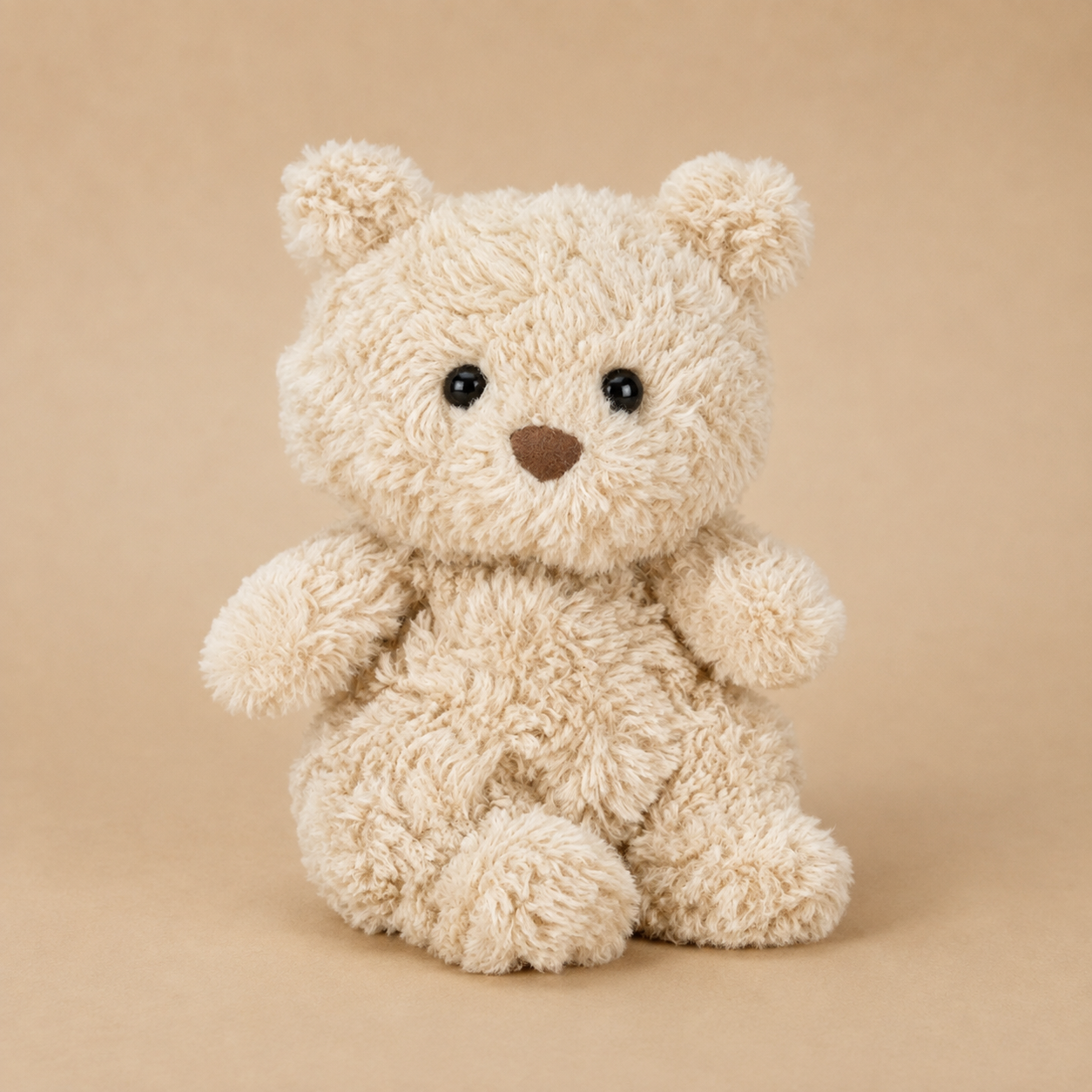 A light creamy tan bear shaped bear stuffed animal toy. 
