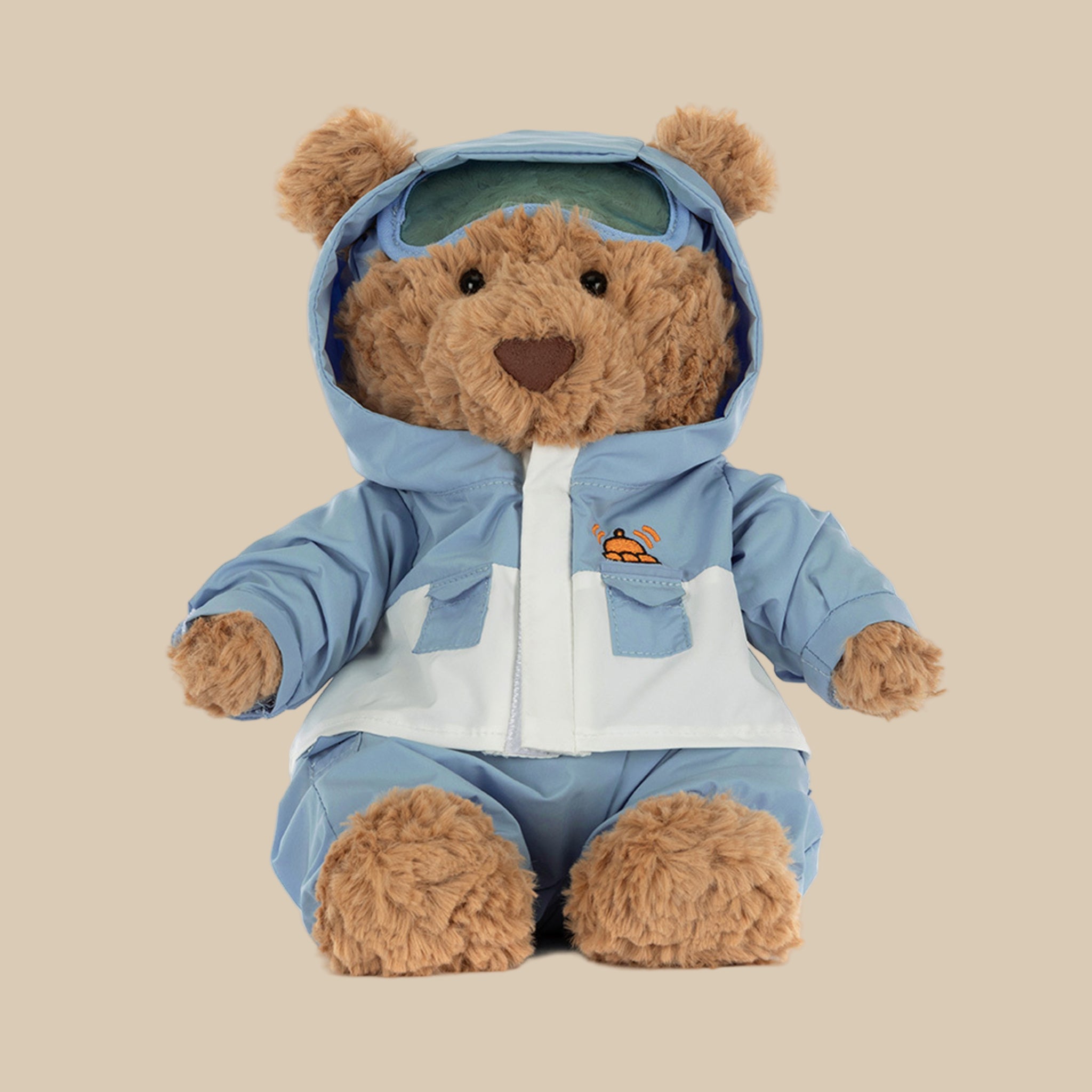 A bear shaped stuffed animal wearing a blue snowsuit. 