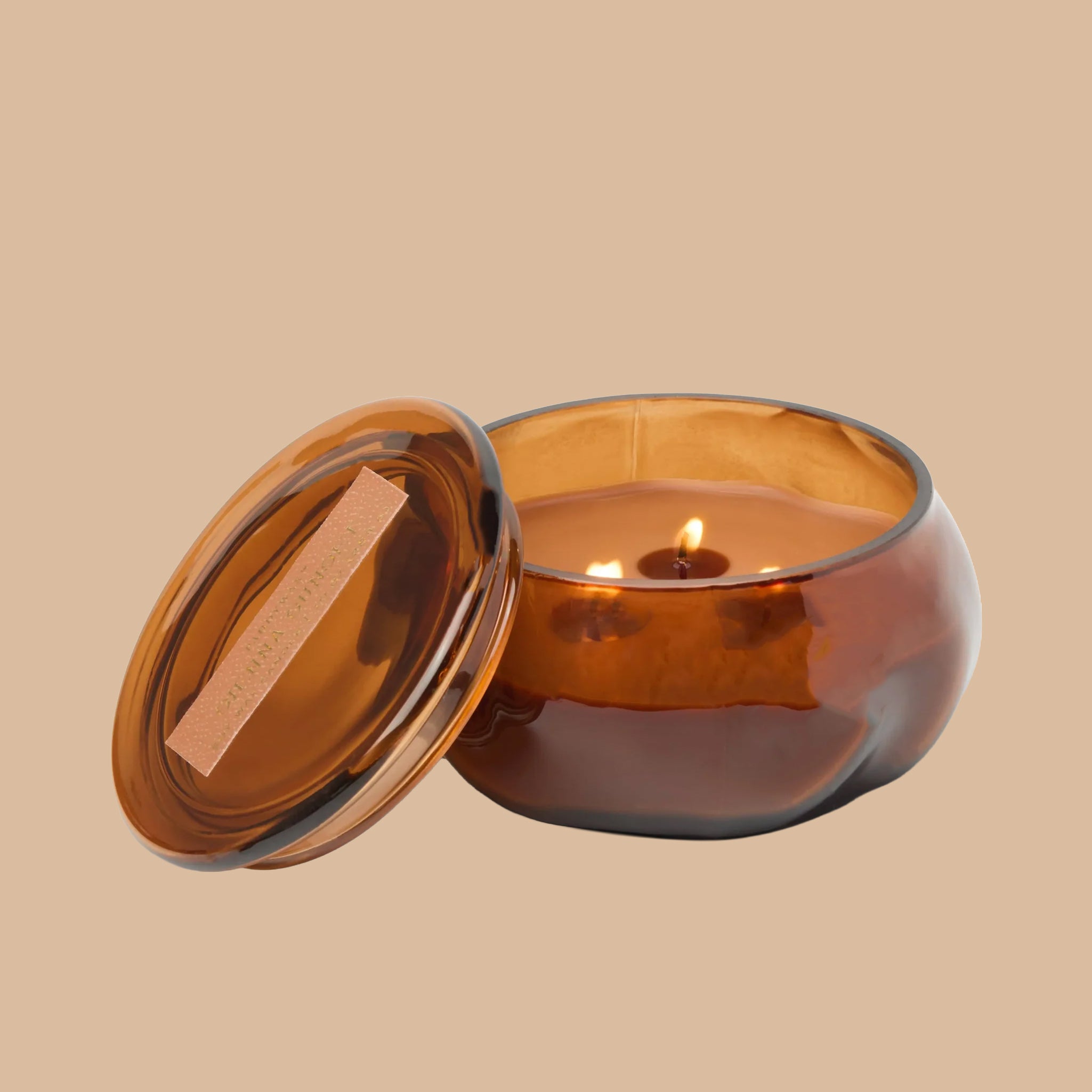 A brown glass jarred candle with a lid. 
