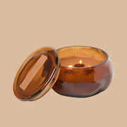 A brown glass jarred candle with a lid. 