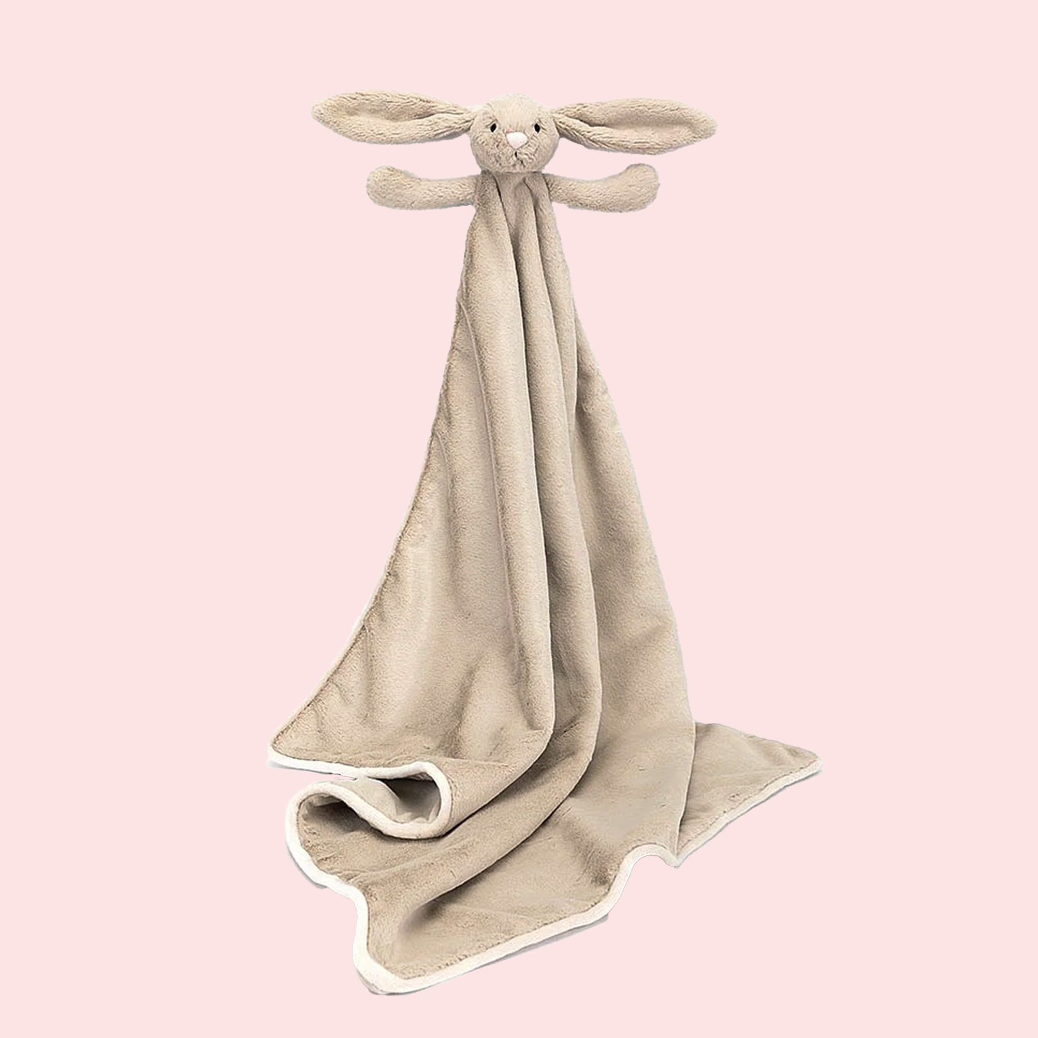 A beige blanket with a bunny head and arms on one corner. 