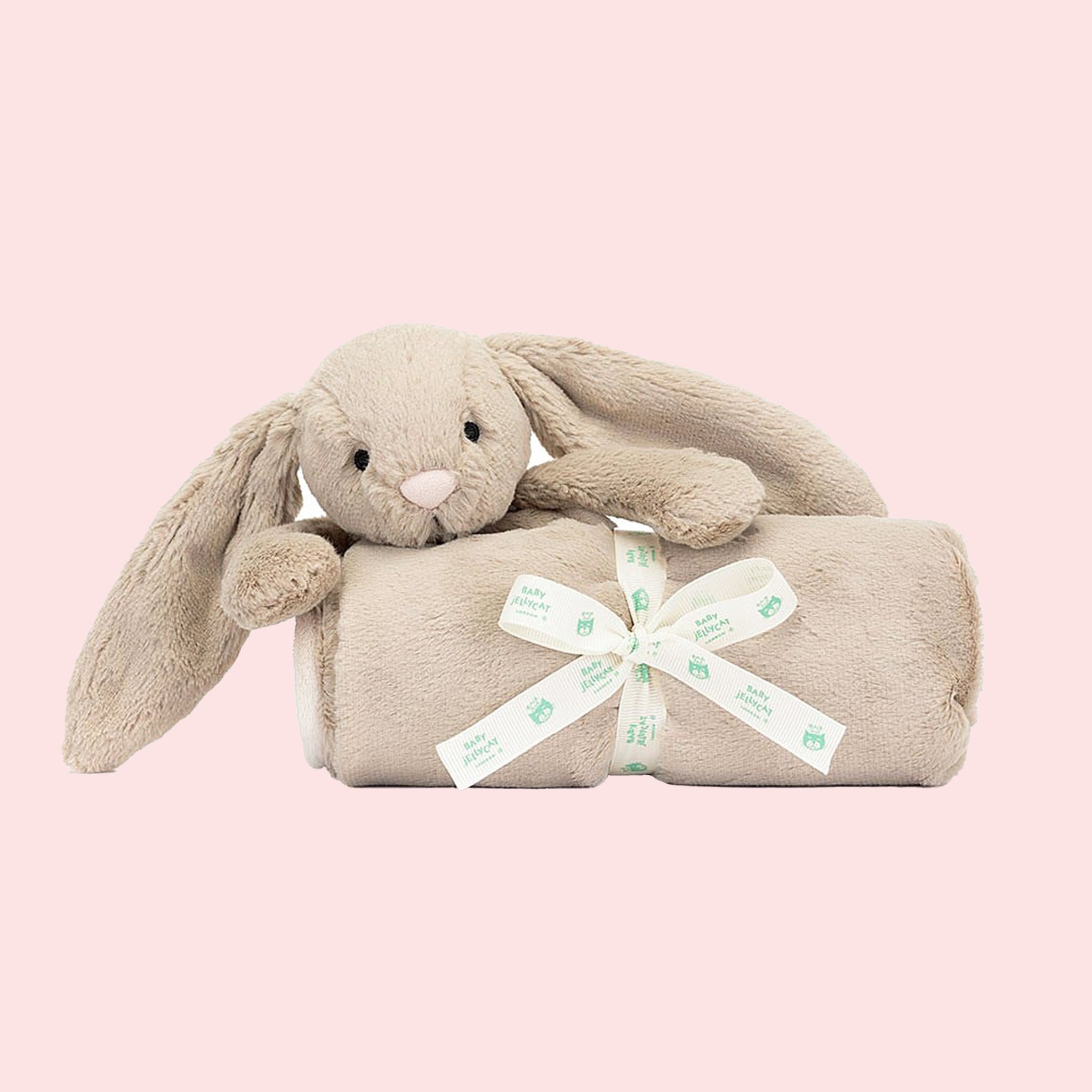 A beige blanket with a bunny head and arms on one corner.