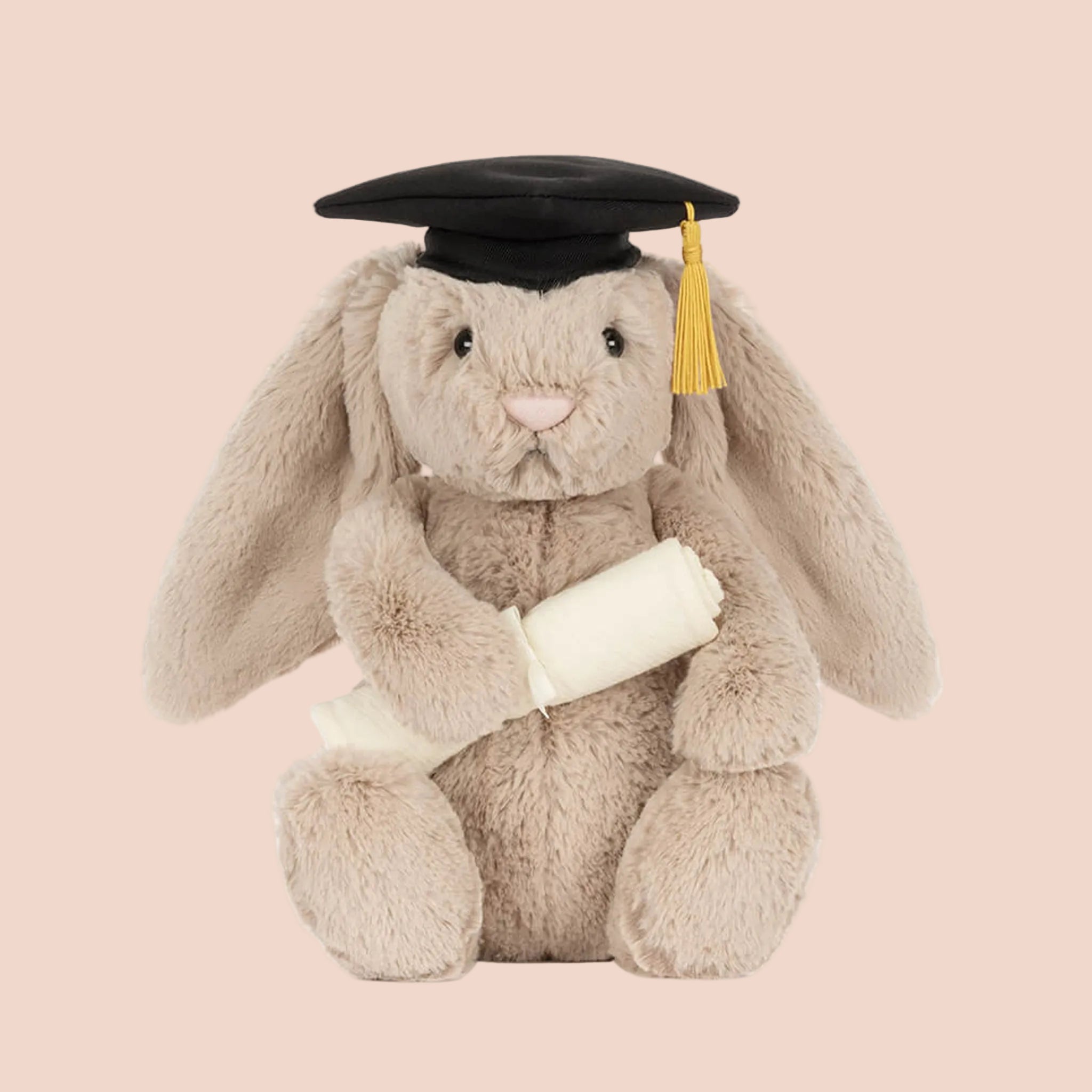 A beige bunny shaped stuffed animal toy with a black graduation cap. 