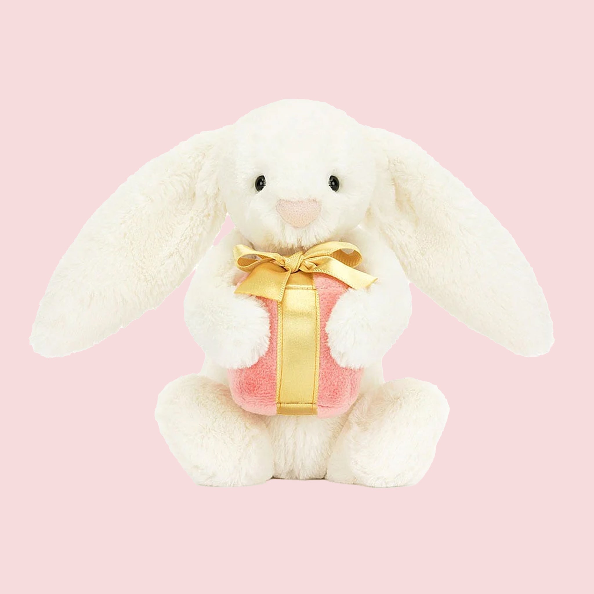 A white stuffed animal bunny holding a pink and gold gift. 
