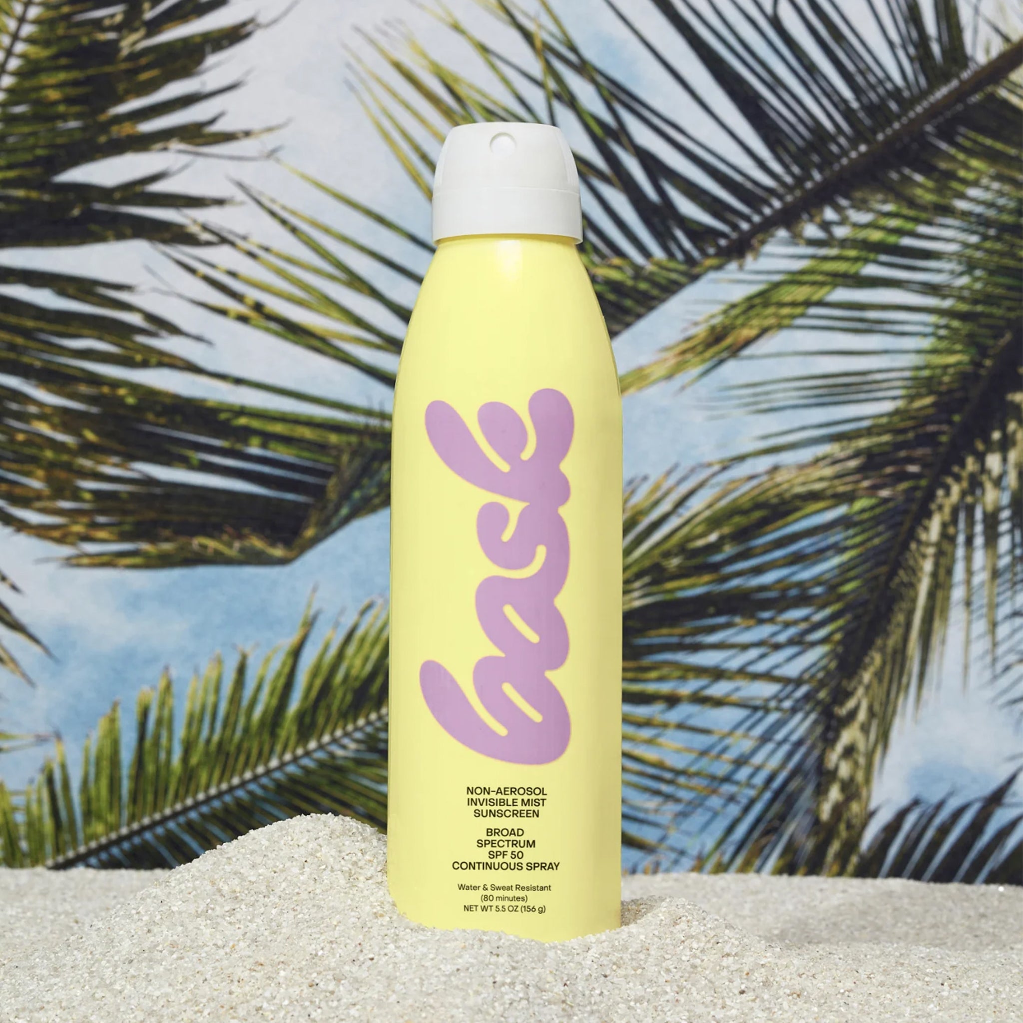 A yellow bottle of spray sunscreen with pink text that reads, "bask".