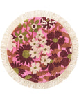 A pink, green and white floral print circular bath mat with a fringe detail around the edge.