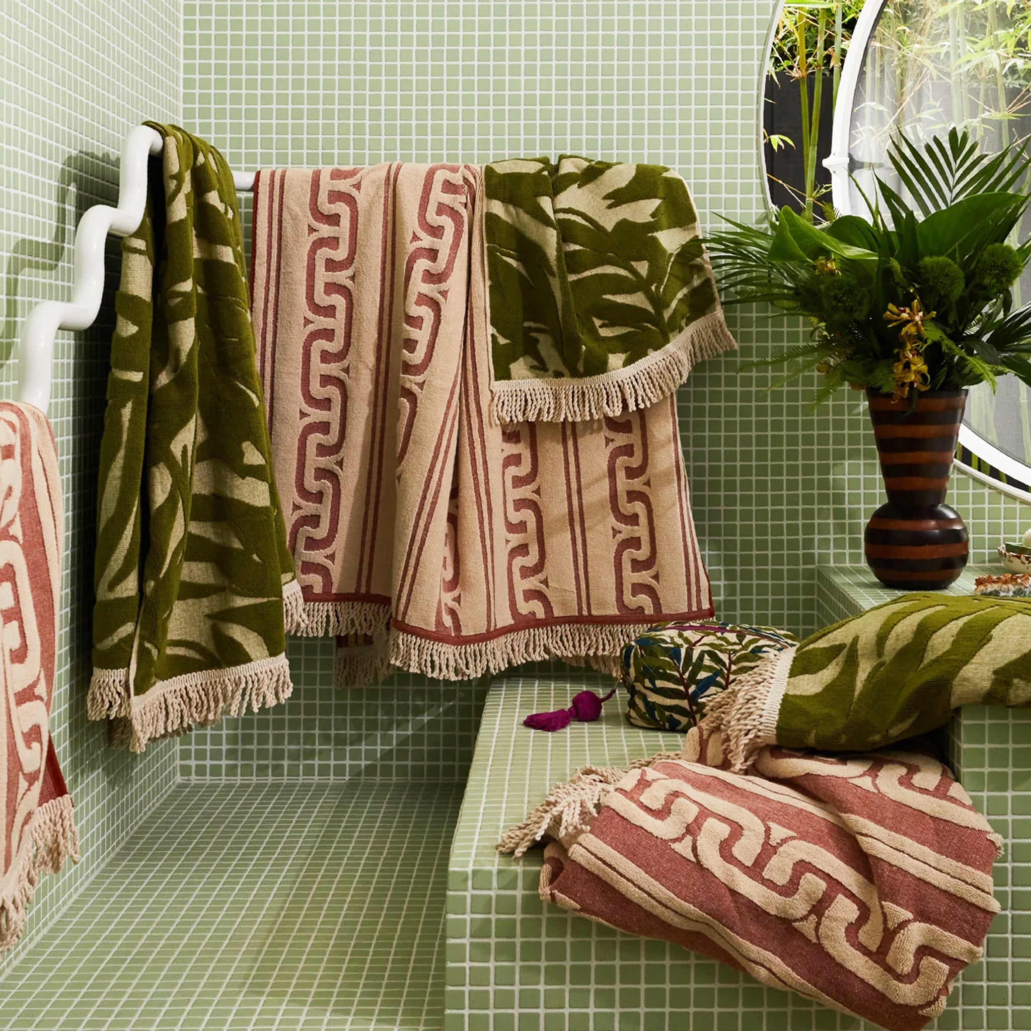 A green and ivory bamboo printed bath towel with tassel ends on both sides.