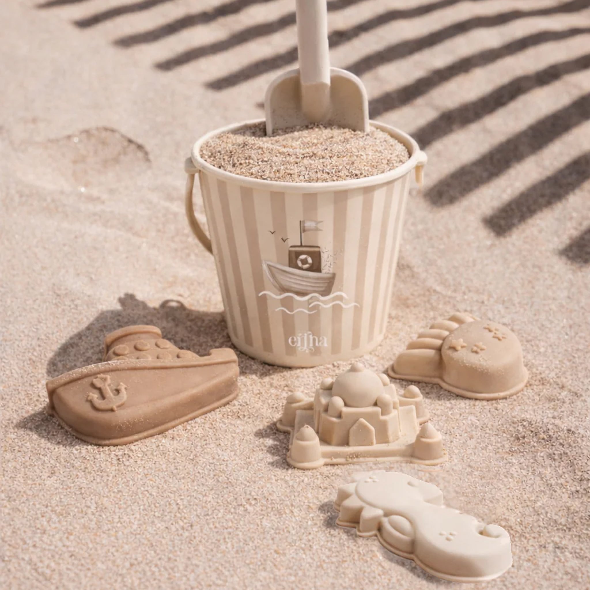Child playing with sand in a decorative bucket on a sandy surface