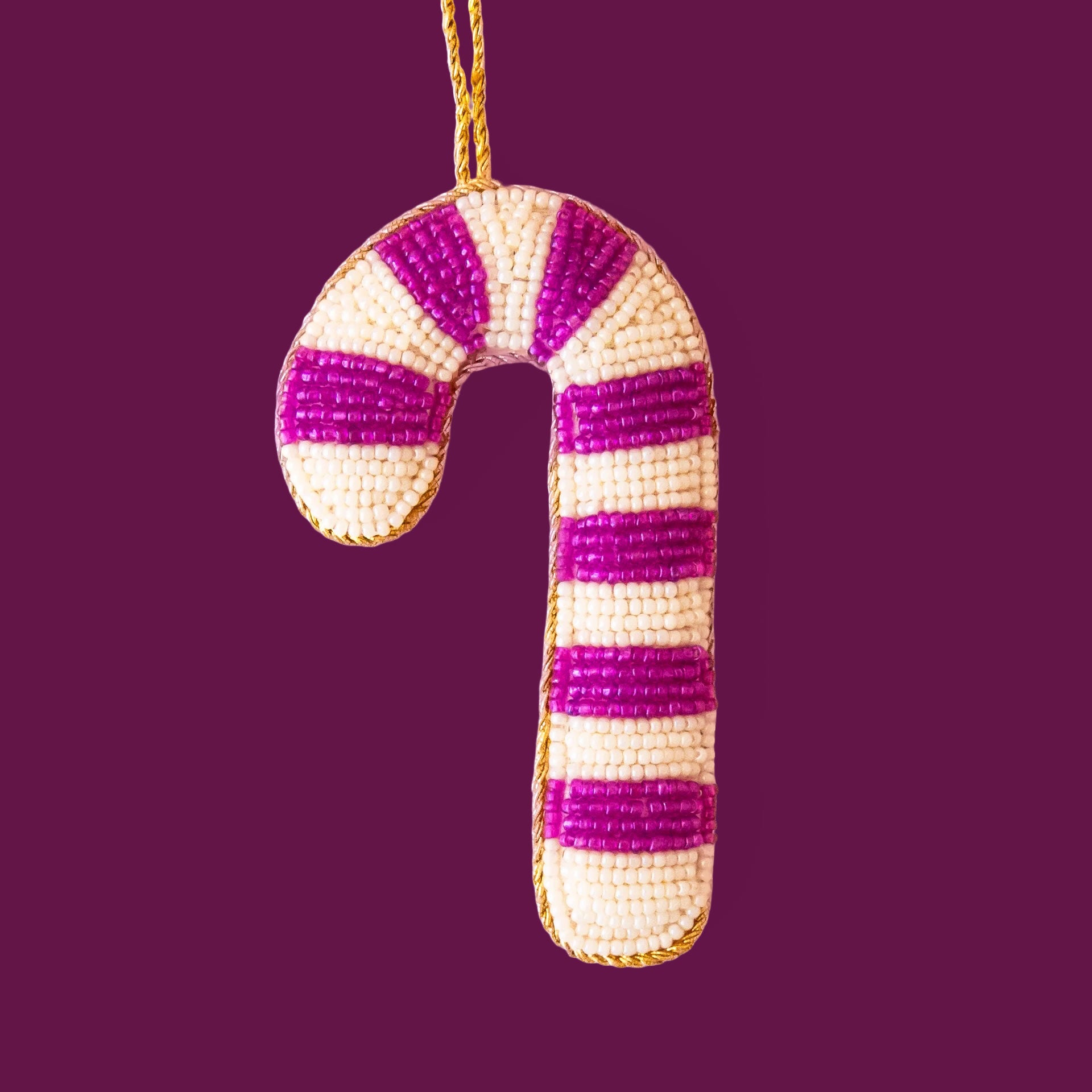 A fuchsia and ivory beaded candy cane shaped ornament. 