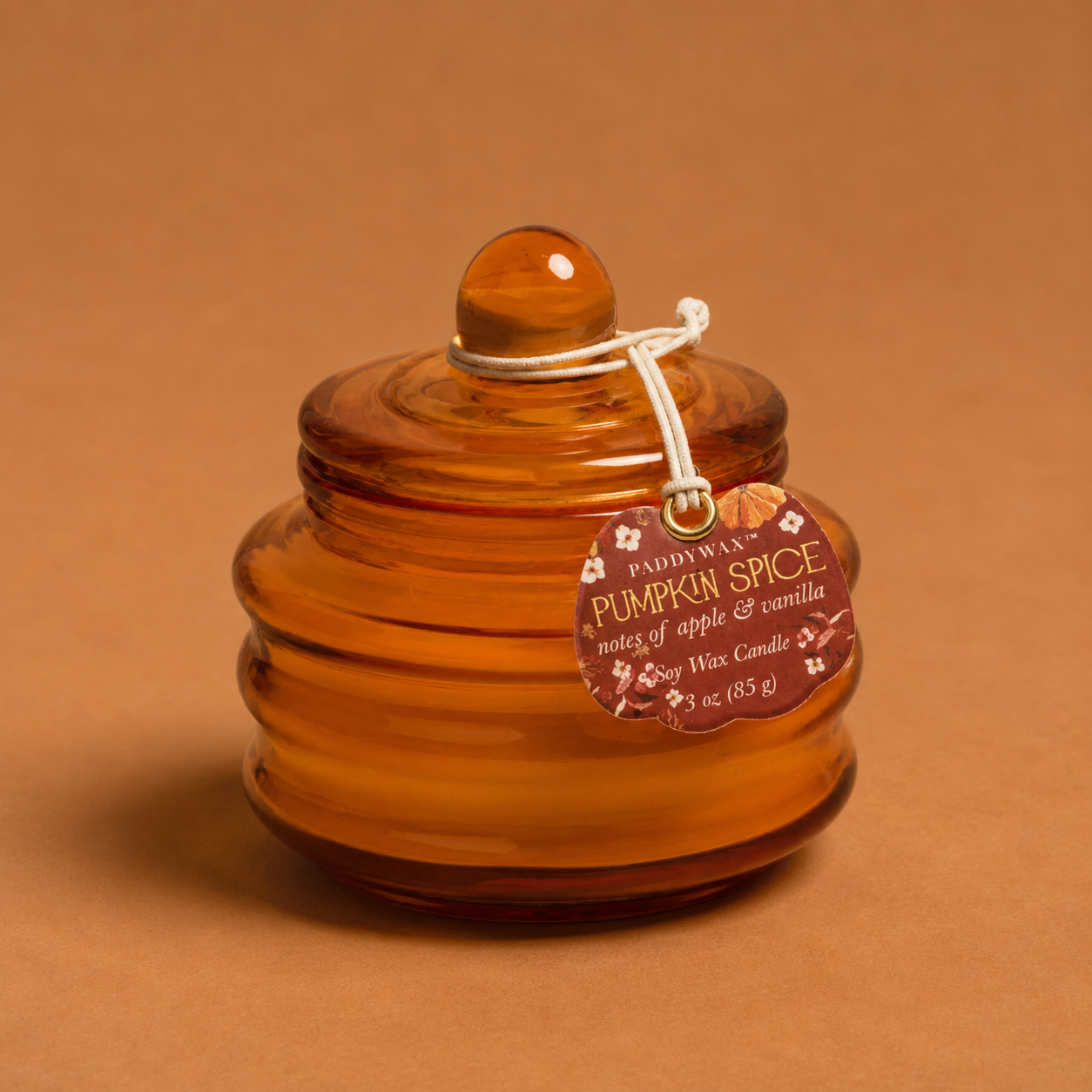 An orange glass candle with a label that reads, 'Paddywax Pumpkin Spice'. 